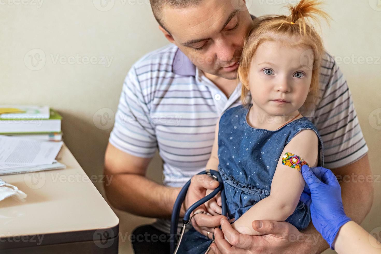 una bambina con suo padre nell'ambulatorio della clinica viene vaccinata contro il coronavirus.il concetto di vaccinazione, immunizzazione, prevenzione contro covid-19. foto