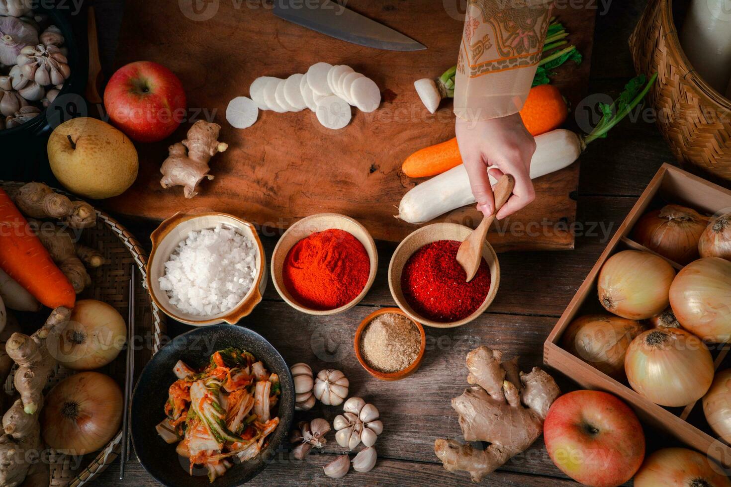 asiatico donne indossare coreano tradizionale costumi hanbok siamo miscelazione fresco saltato in padella e kimchi ingredienti con ingredienti come come sale, aglio, gochugaru, fresco verdure. foto