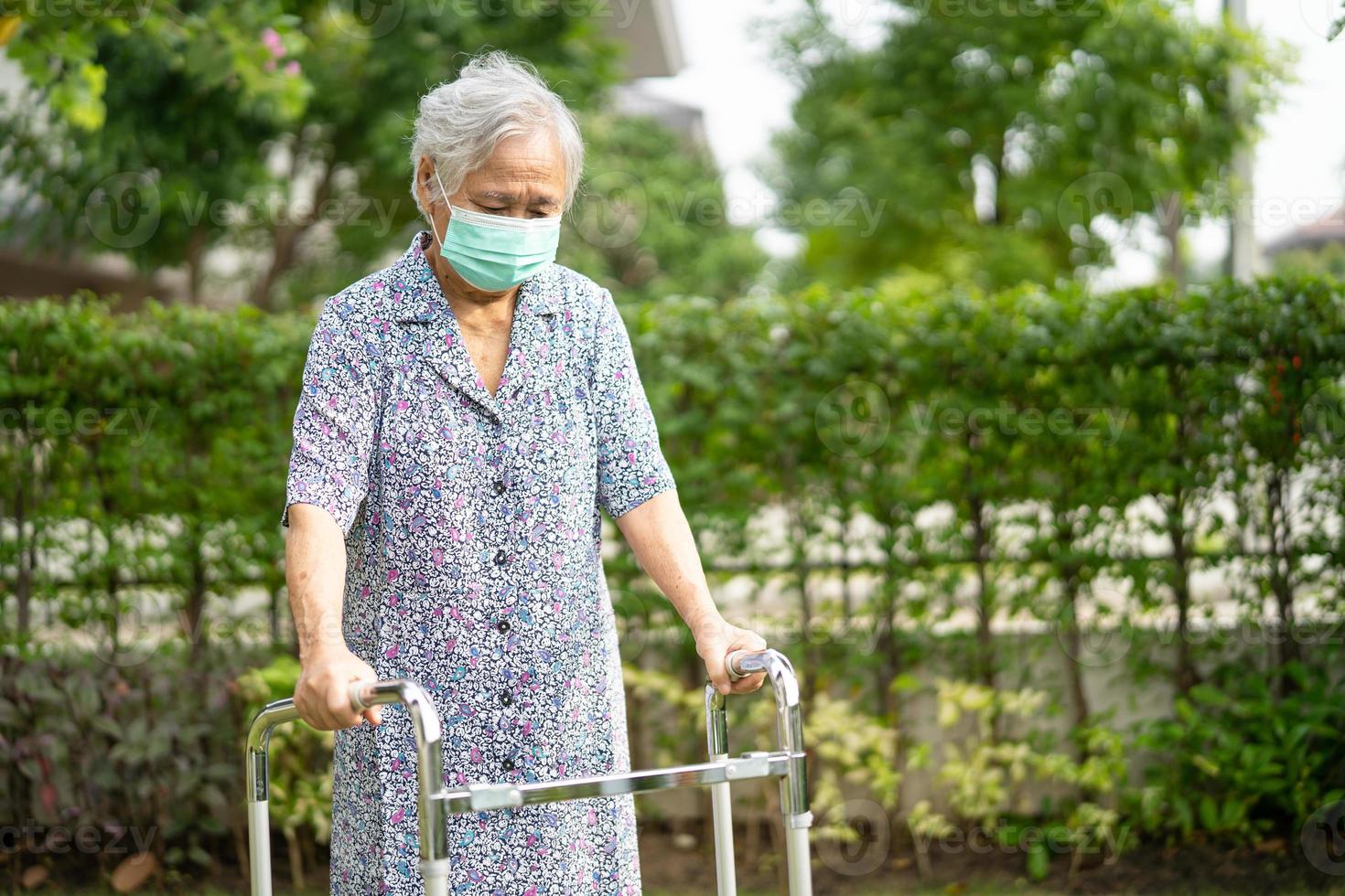 la donna anziana o anziana asiatica cammina con il deambulatore e indossa una maschera facciale per proteggere l'infezione di sicurezza e uccidere il nuovo virus covid-19 del coronavirus. foto