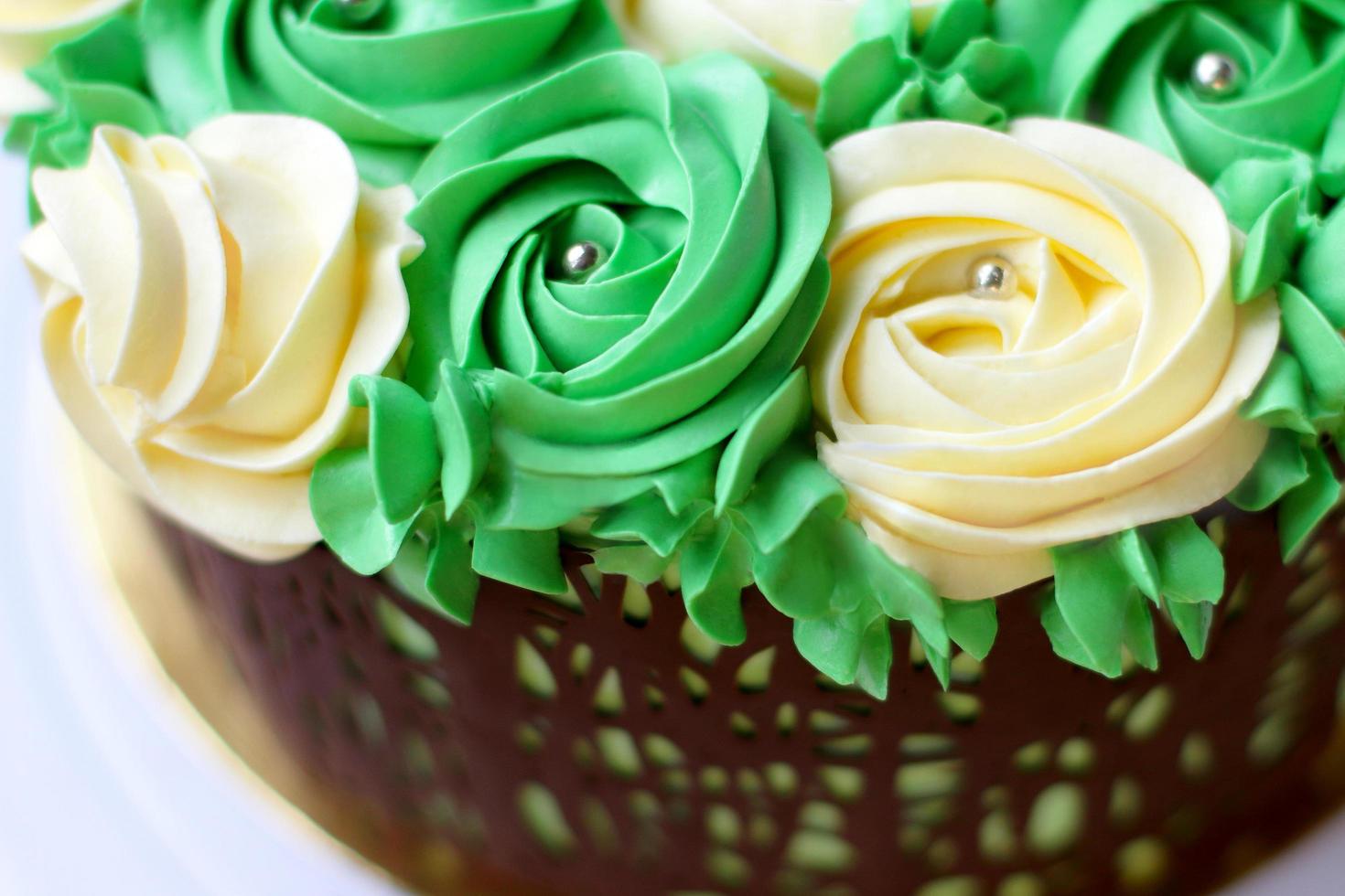 splendida torta fatta in casa ricoperta di rose gialle e verdi fatta di crema al burro, cornice di cioccolato, glassa su sfondo bianco foto