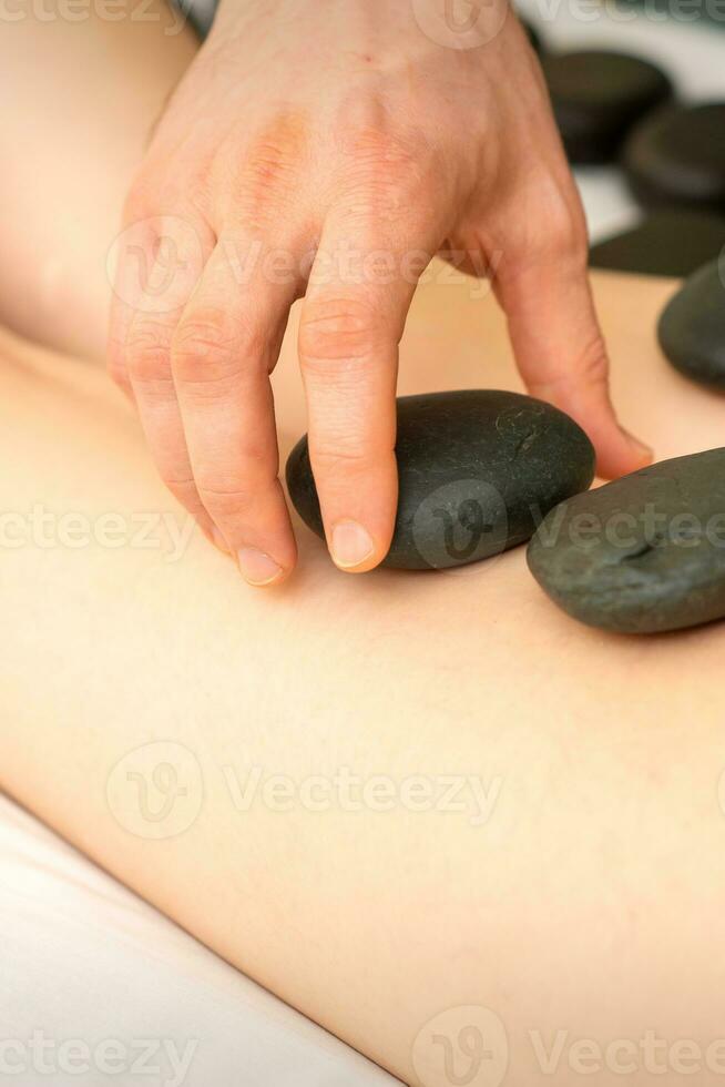 un' donna ottenere terme caldo pietra terapia gambe massaggio procedura nel un' bellezza salone. foto
