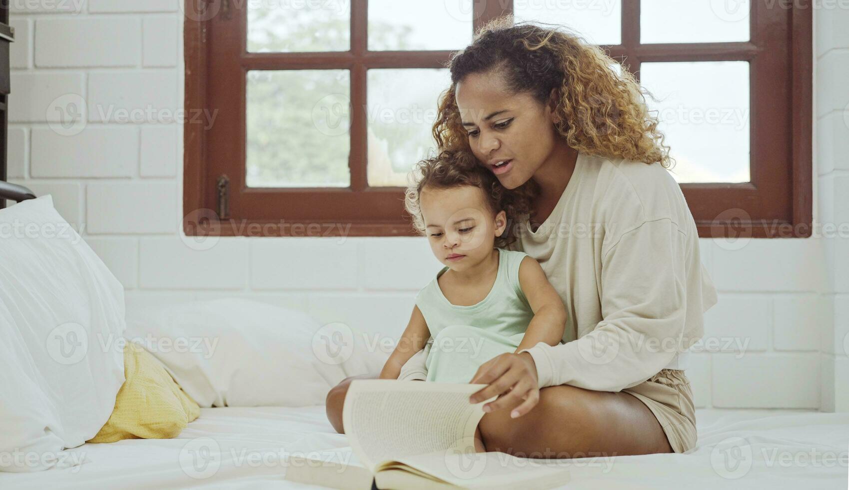 giovane madre è lettura un' libro con sua figlia. foto