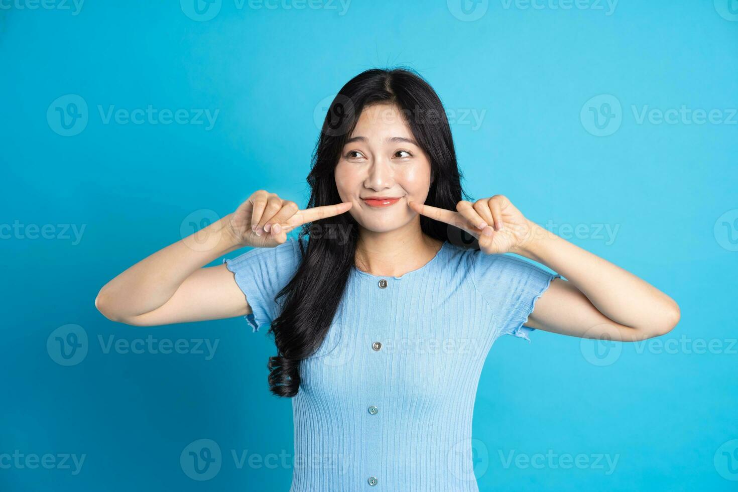 ritratto di un' contento sorridente asiatico ragazza in posa su un' blu sfondo foto