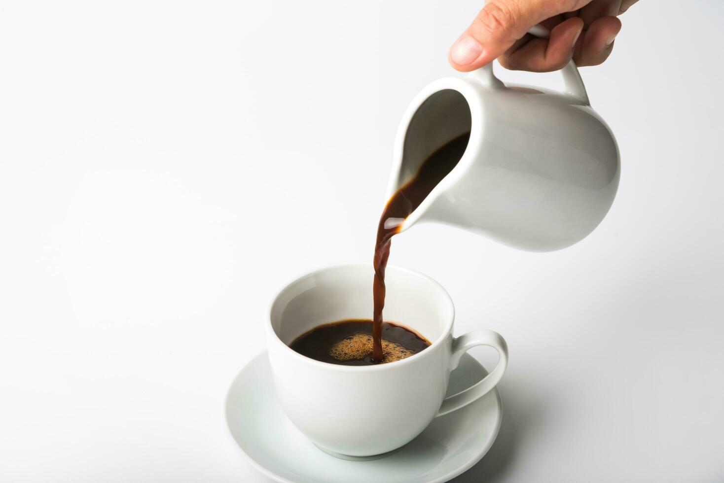 versando una tazza di caffè su sfondo bianco foto