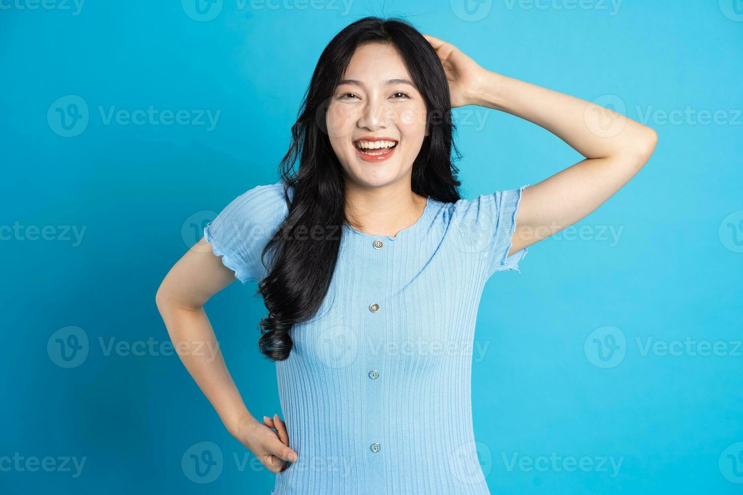 ritratto di un' contento sorridente asiatico ragazza in posa su un' blu sfondo foto
