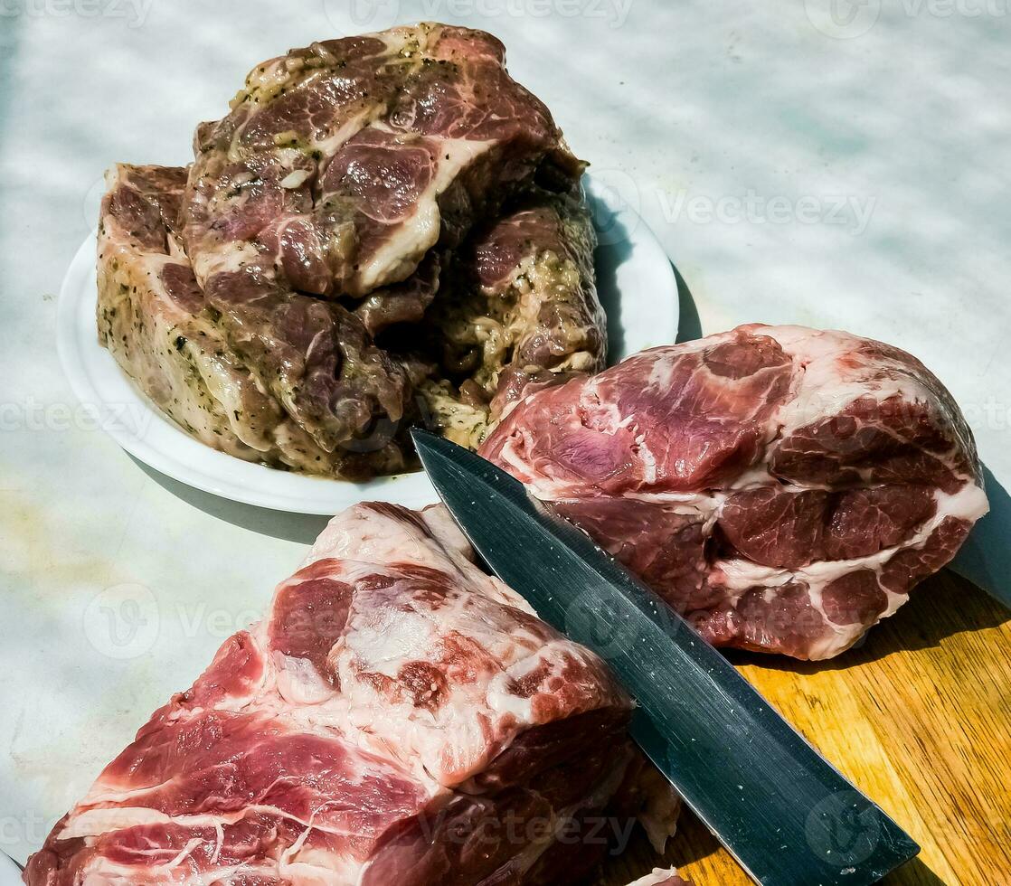 fresco pezzi di Maiale collo su un' di legno cucina tavola e marinato bistecche su un' piatto. pezzi di maiale carne avvicinamento foto