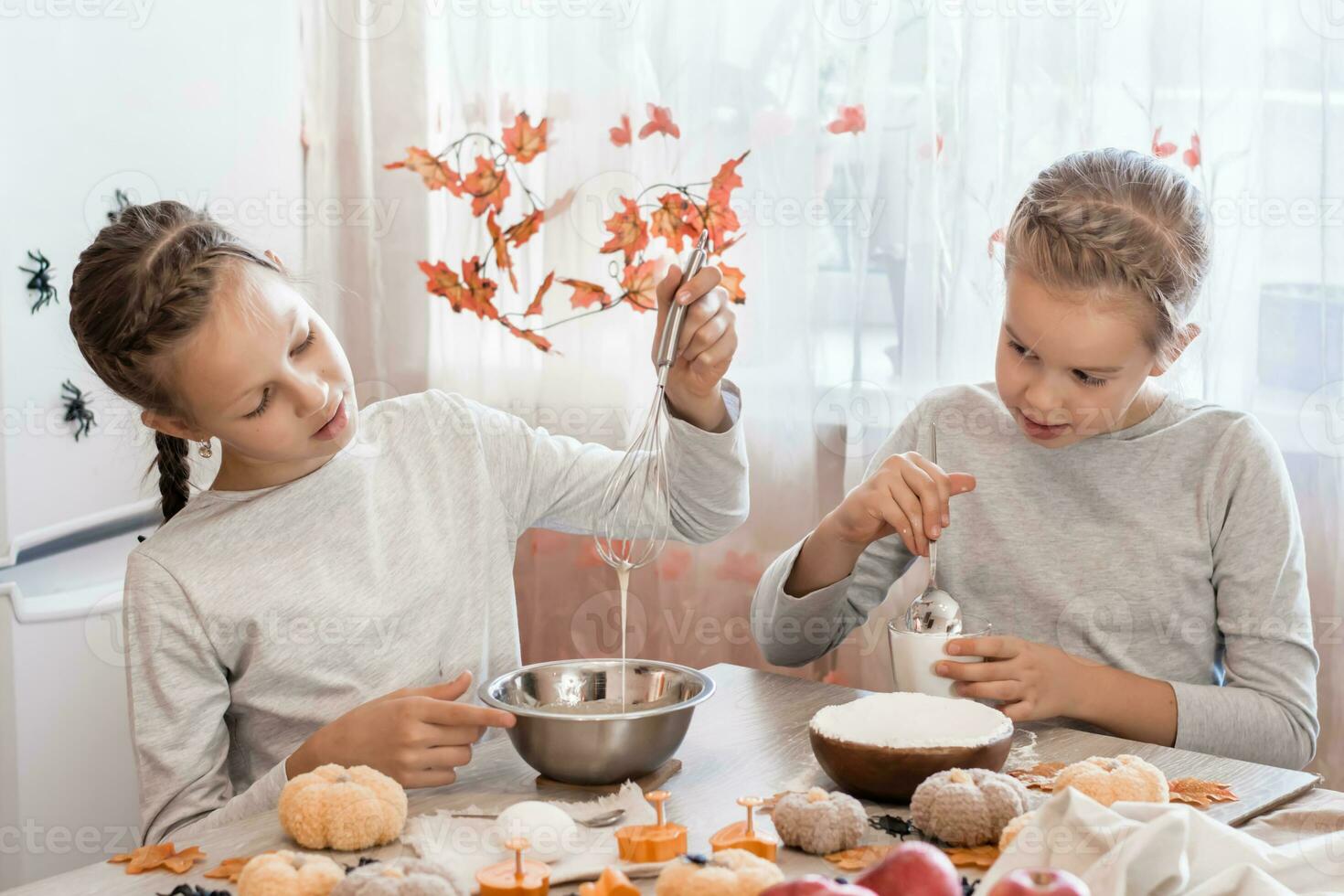 ossequi e preparazioni per il celebrazione di Halloween. Due carino sorelle preparazione Pan di zenzero Impasto per cottura al forno biscotti per Halloween nel casa cucina. foto