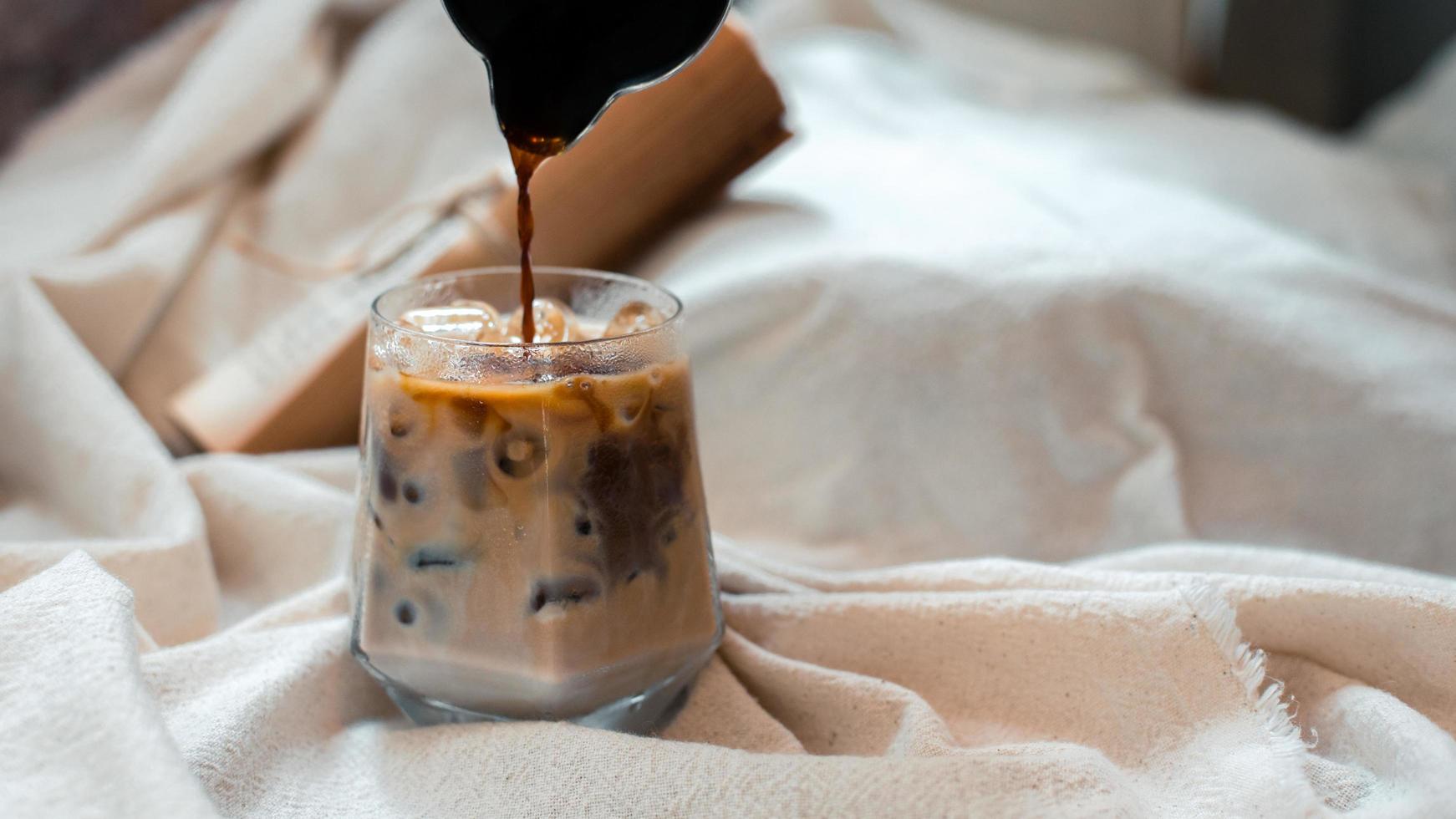 barista che versa il latte in un bicchiere di caffè freddo foto