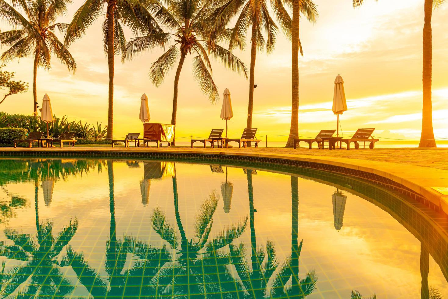 ombrellone e sedia intorno alla piscina nel resort dell'hotel con l'alba al mattino foto