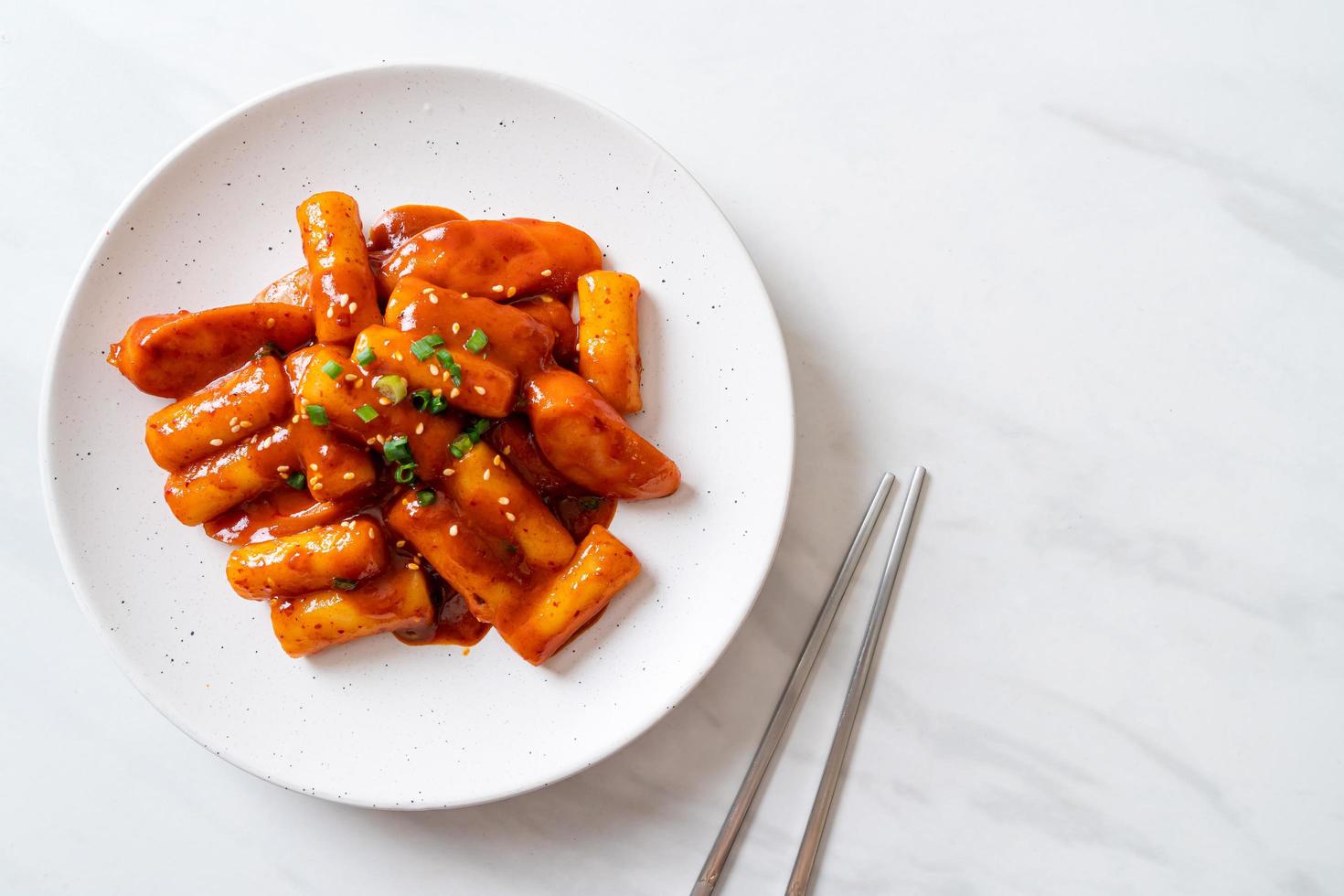 Stecco di torta di riso coreano con salsiccia in salsa piccante - tteokbokki foto