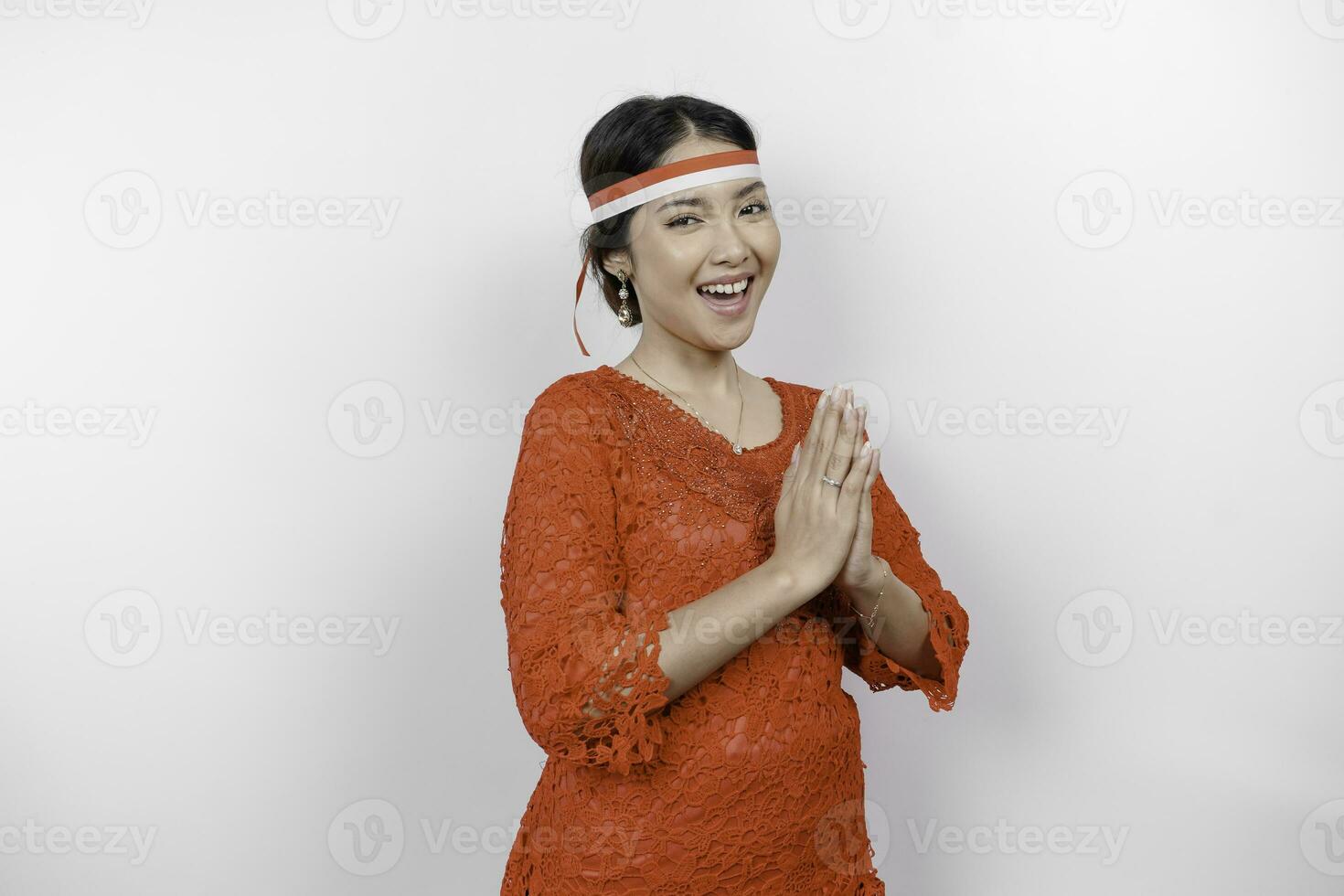 un' amichevole indonesiano donna è indossare rosso kebaya Esprimere a gesti tradizionale saluto e dell'Indonesia bandiera fascia per capelli per celebrare Indonesia indipendenza giorno. isolato di bianca sfondo. foto