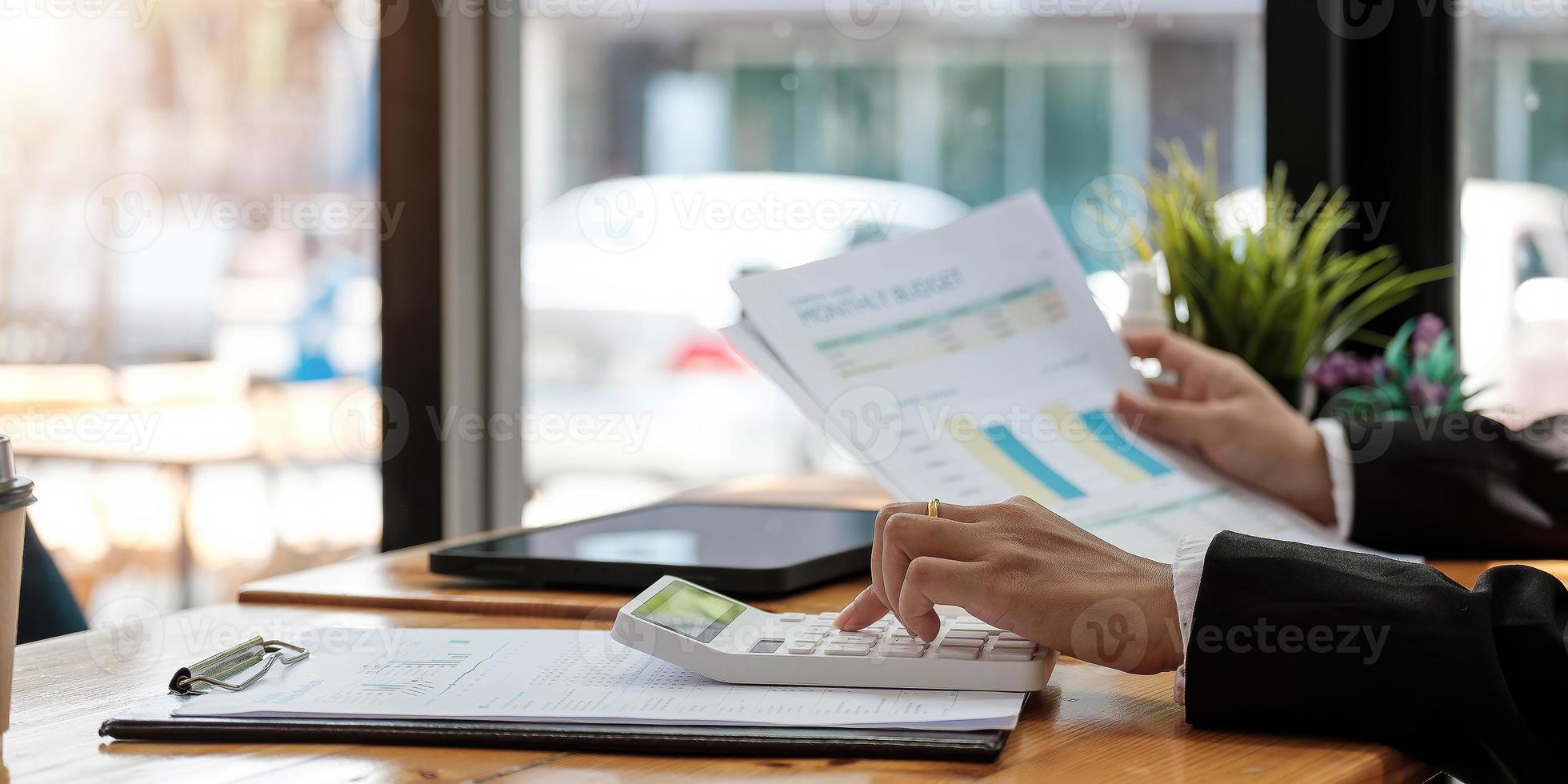 donna con relazione finanziaria e calcolatrice. donna che usa la calcolatrice per calcolare il rapporto al tavolo in ufficio foto