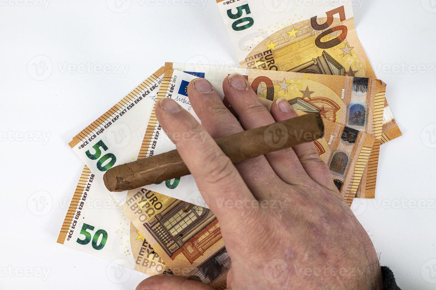 Banconote da 50 euro con sigaro in mano d'uomo foto