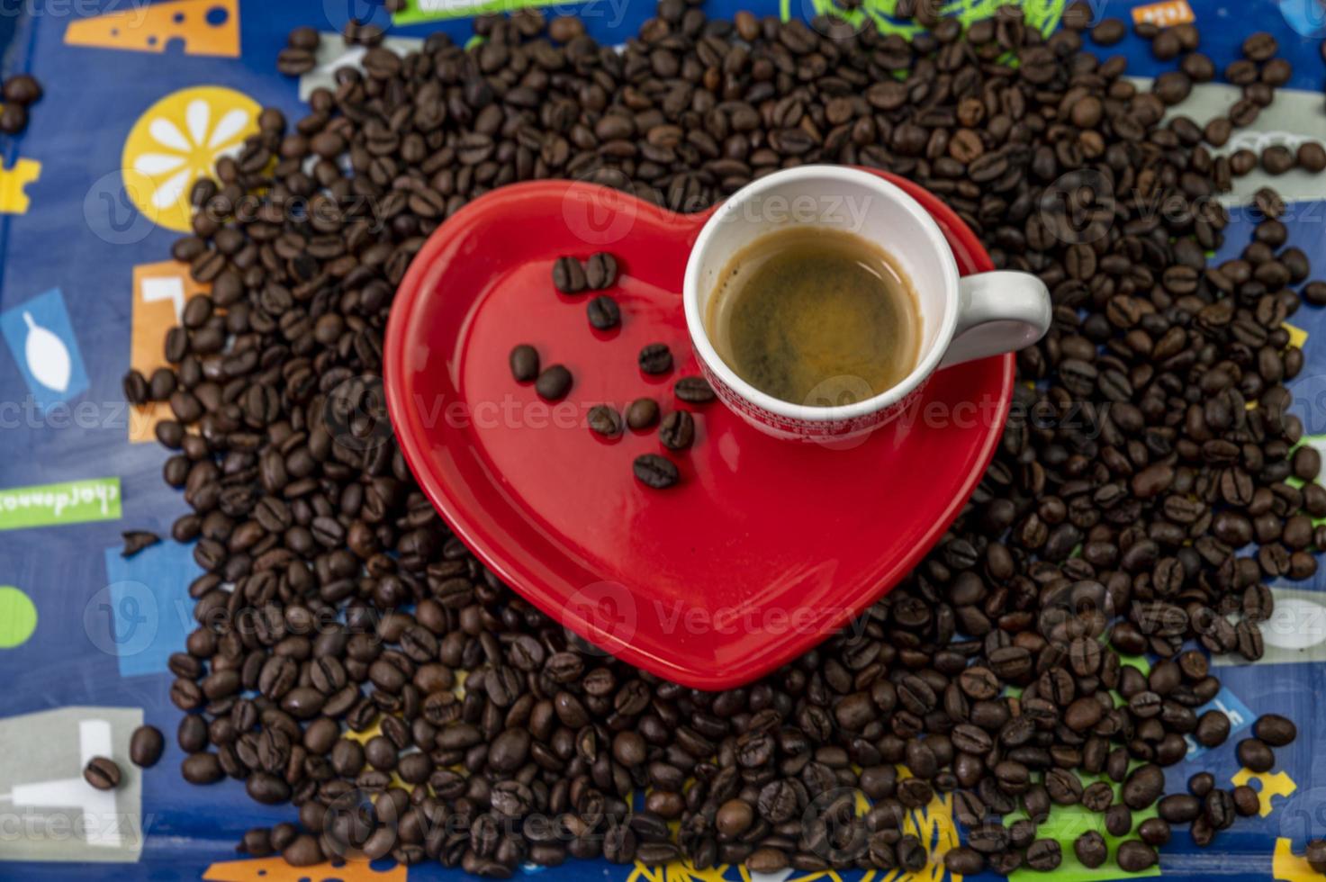 composizione in chicchi di caffè con tazza e piattino a forma di cuore foto