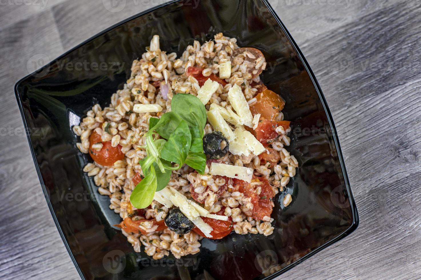 servito su un piatto nero di insalata di farro foto