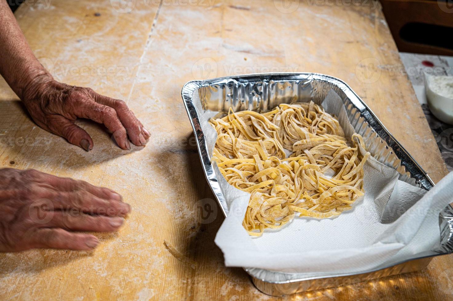 la nonna dispone le tagliatelle sulla soletta di alluminio foto