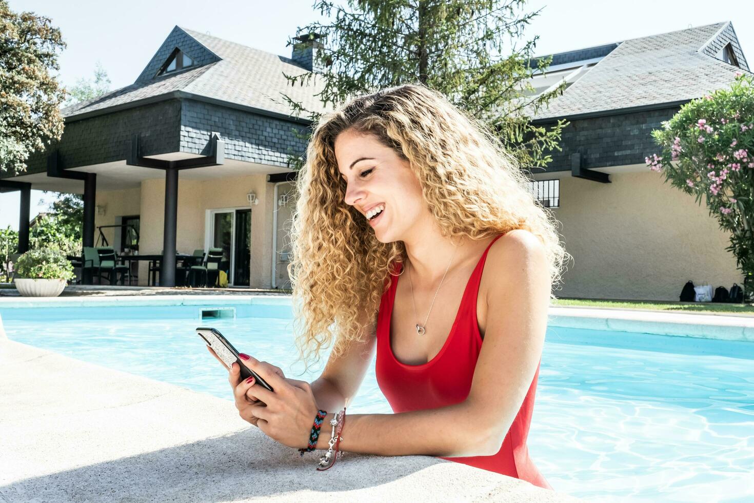 donna nel un' rosso costume da bagno dentro un' piscina utilizzando sua cellula Telefono foto