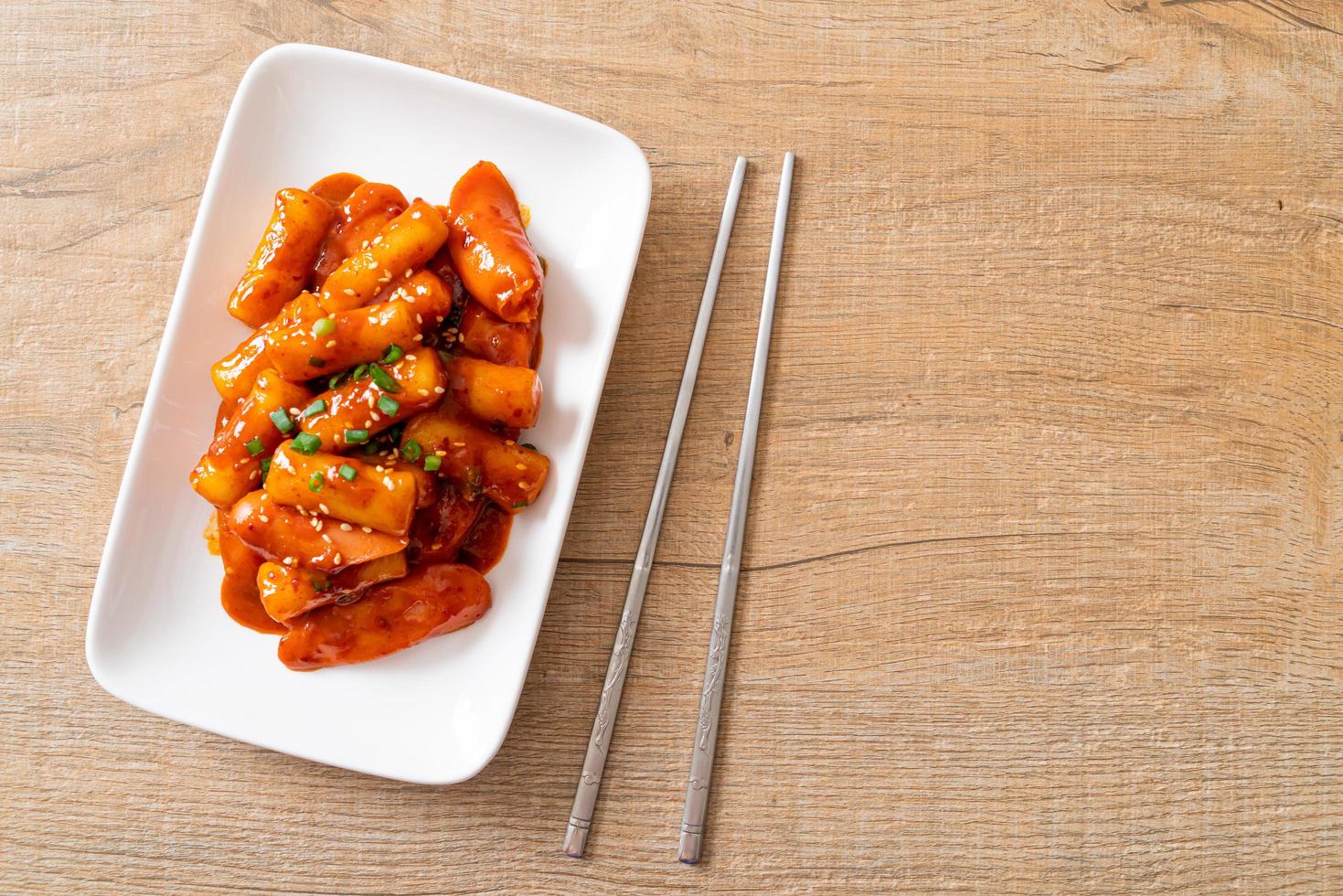 Stecco di torta di riso coreano con salsiccia in salsa piccante - tteokbokki foto