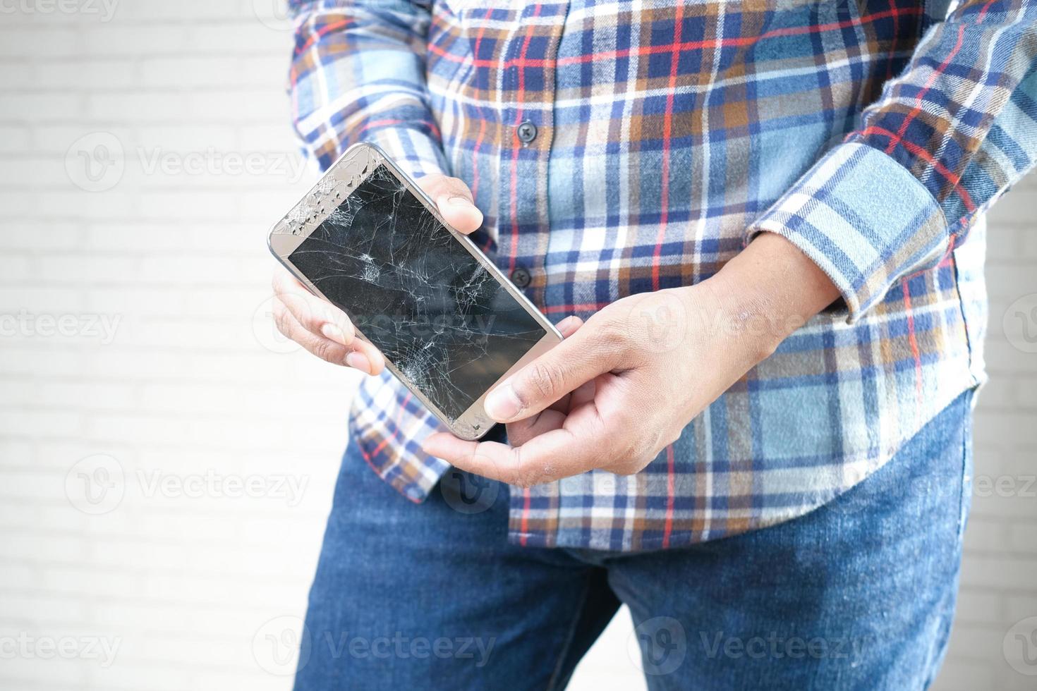 primo piano della mano dell'uomo che tiene lo smartphone rotto. foto