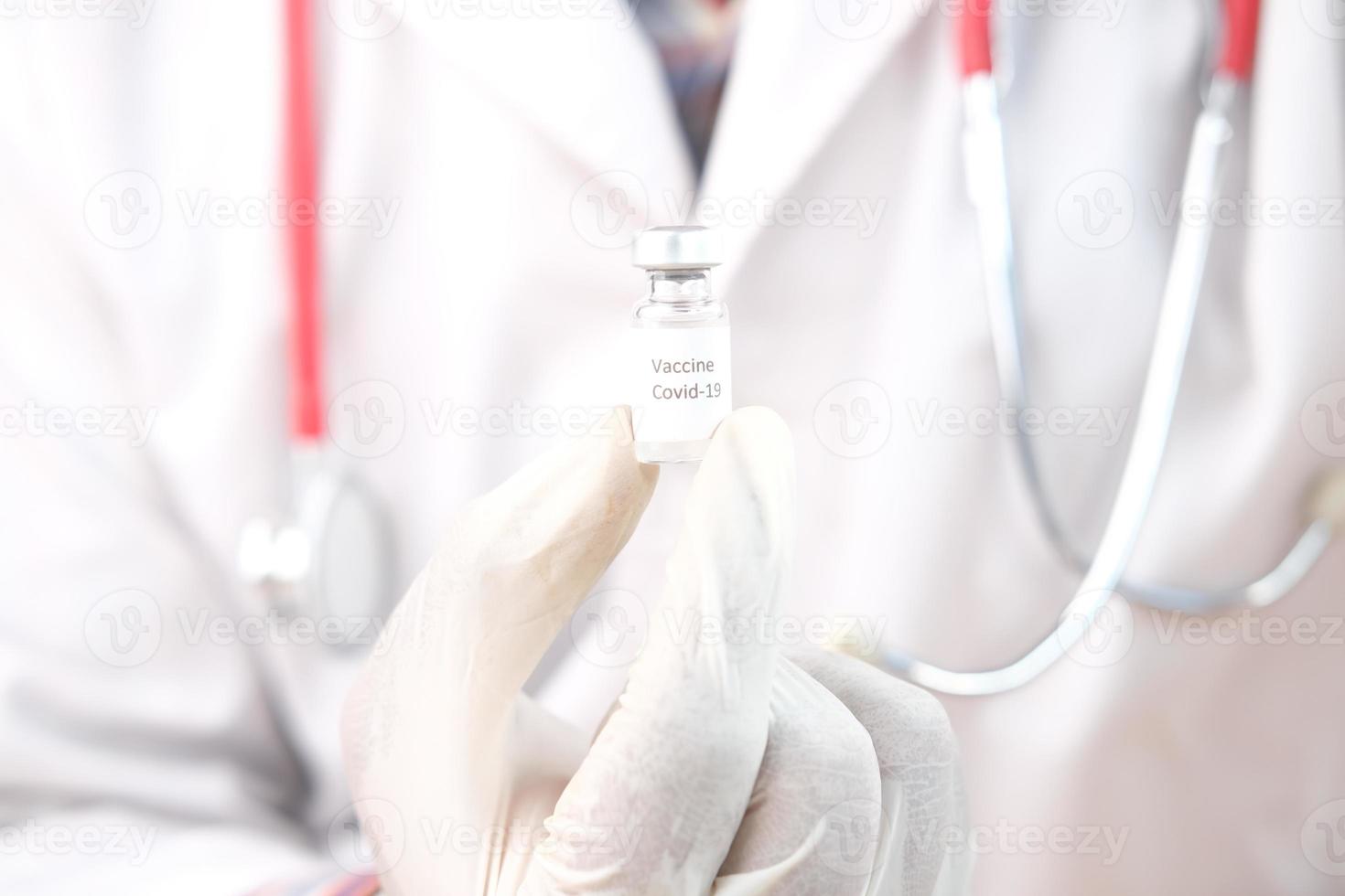 mano in guanti di lattice che tengono il vaccino in fiala di vetro, con spazio di copia foto