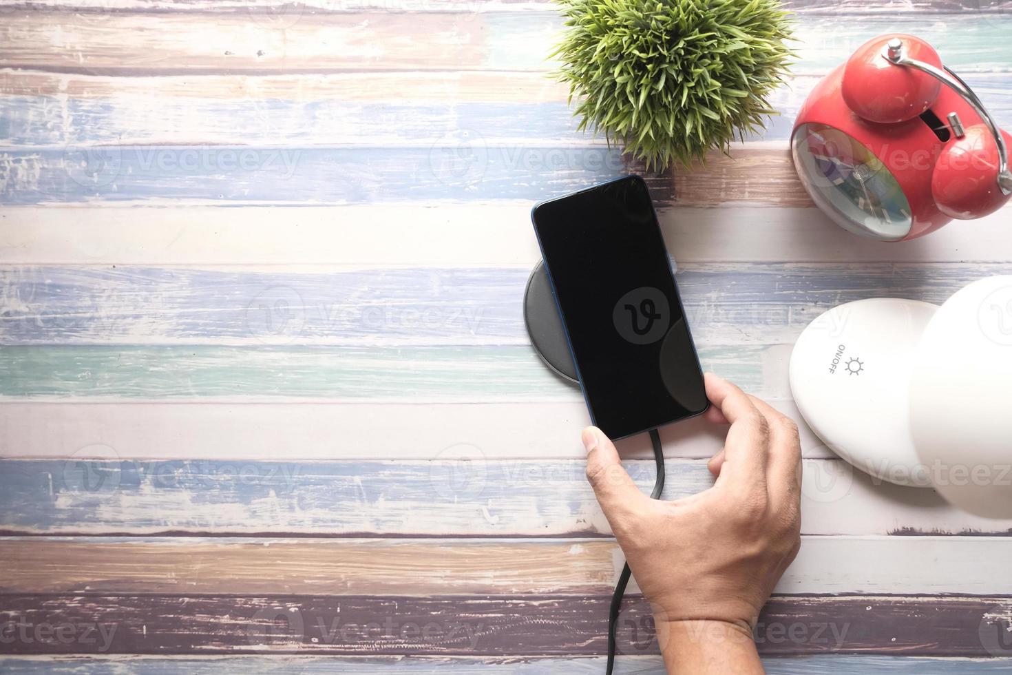 smartphone in carica tramite pad di ricarica wireless, vista dall'alto foto