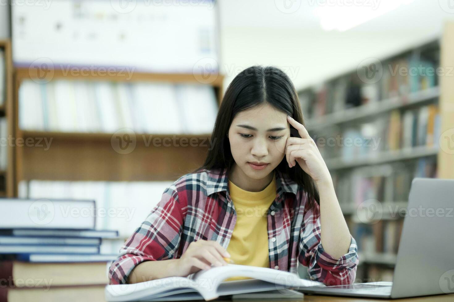 giovane Università alunno utilizzando il computer portatile per in linea apprendimento, ricerca e apprendimento a biblioteca. foto