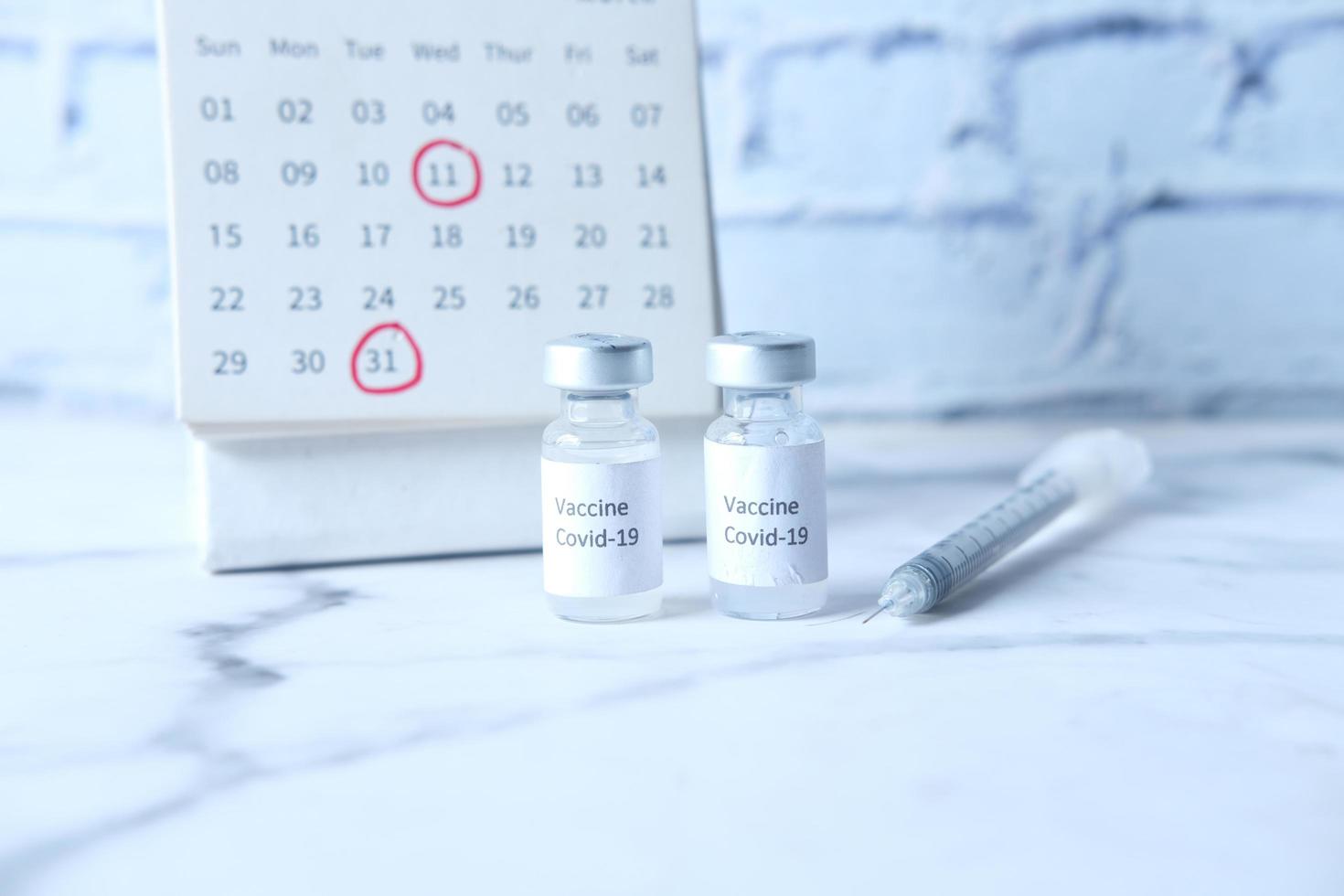 vaccino contro il coronavirus, siringa e calendario sul tavolo foto