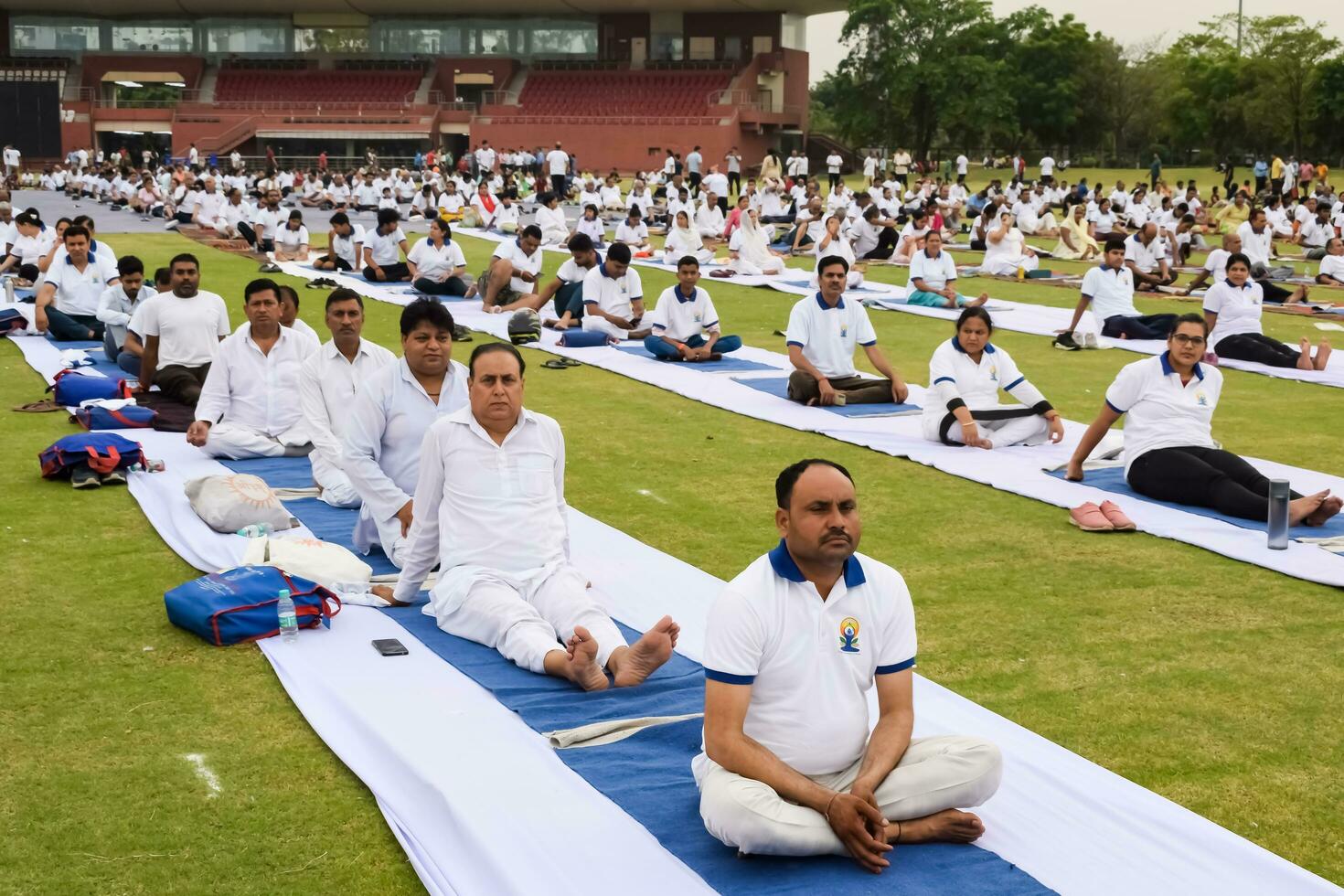 nuovo delhi, India, giugno 21, 2023 - gruppo yoga esercizio sessione per persone a yamuna gli sport complesso nel delhi su internazionale yoga giorno, grande gruppo di adulti frequentando yoga classe nel cricket stadio foto