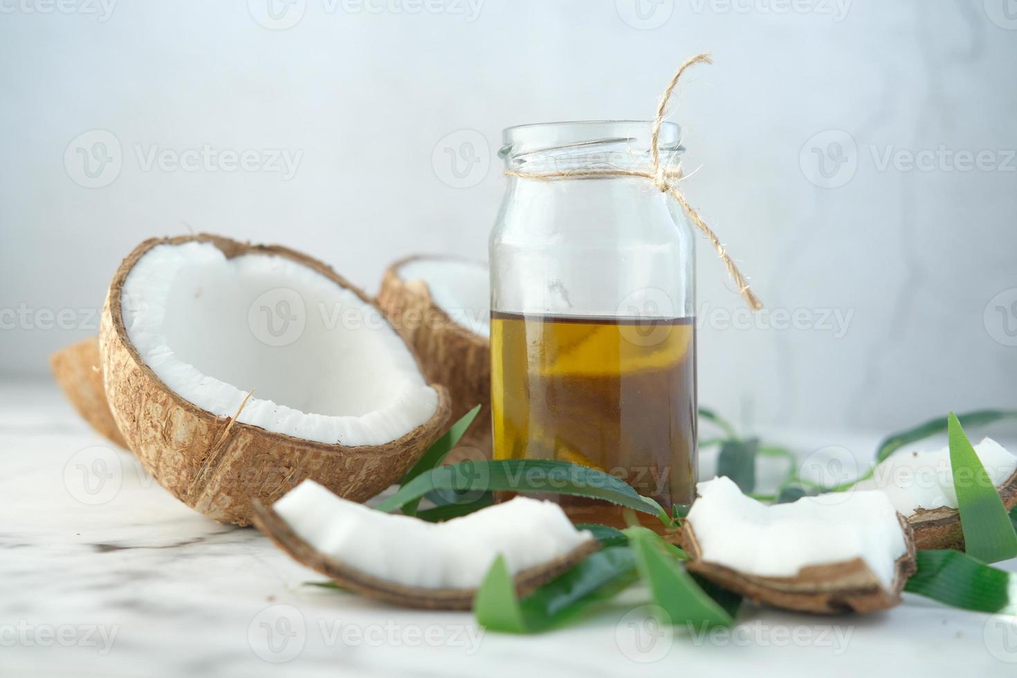 fetta di cocco fresco e bottiglia di olio su un tavolo foto
