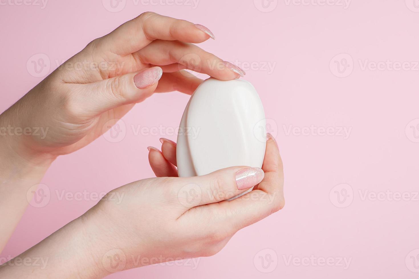 la donna igienizza le mani con sapone antibatterico su uno sfondo rosa. prevenzione del coronavirus, assistenza sanitaria. foto