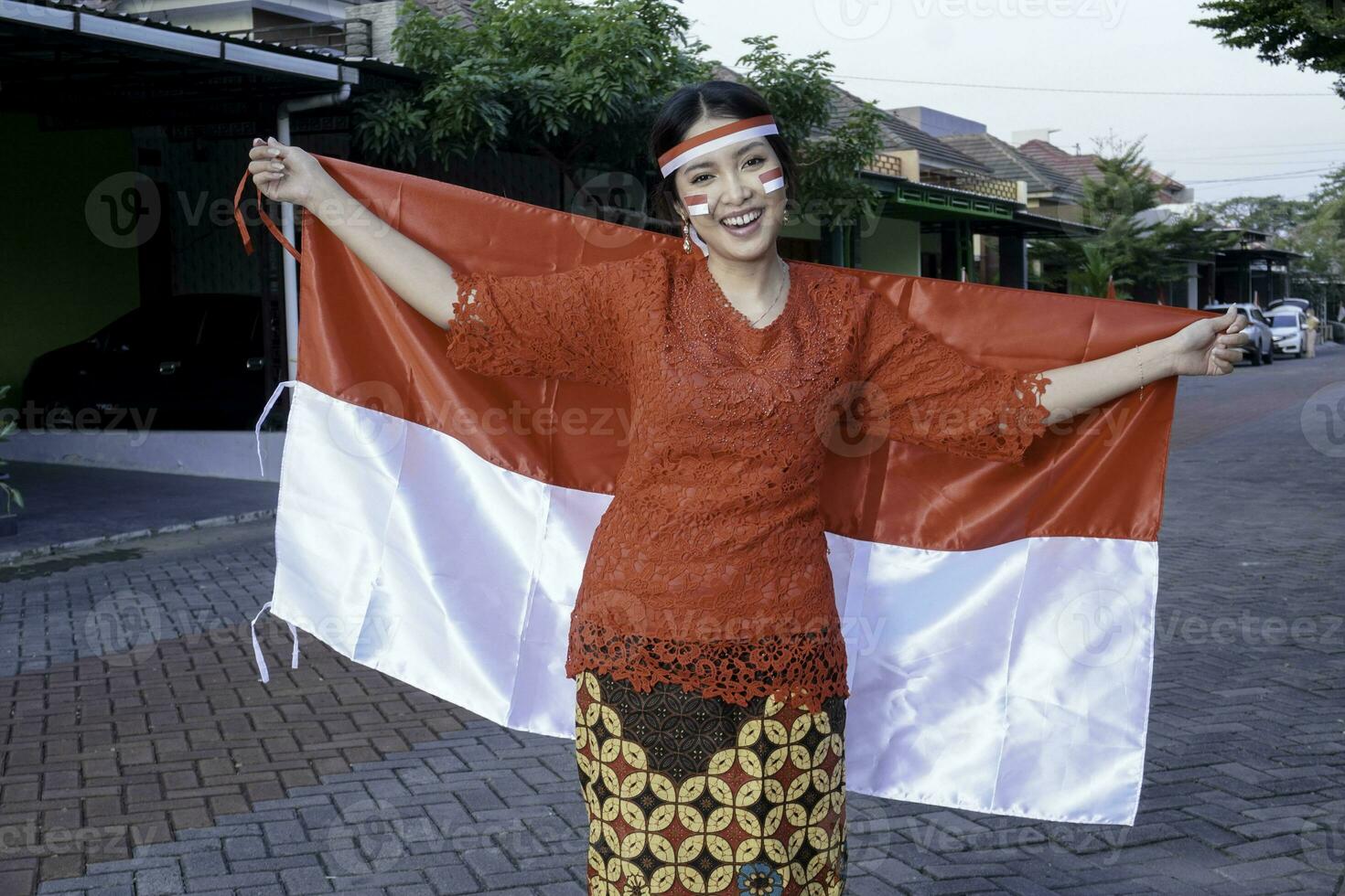 contento sorridente indonesiano donna indossare rosso kebaya Tenere dell'Indonesia bandiera per celebrare Indonesia indipendenza giorno. all'aperto servizio fotografico concetto foto