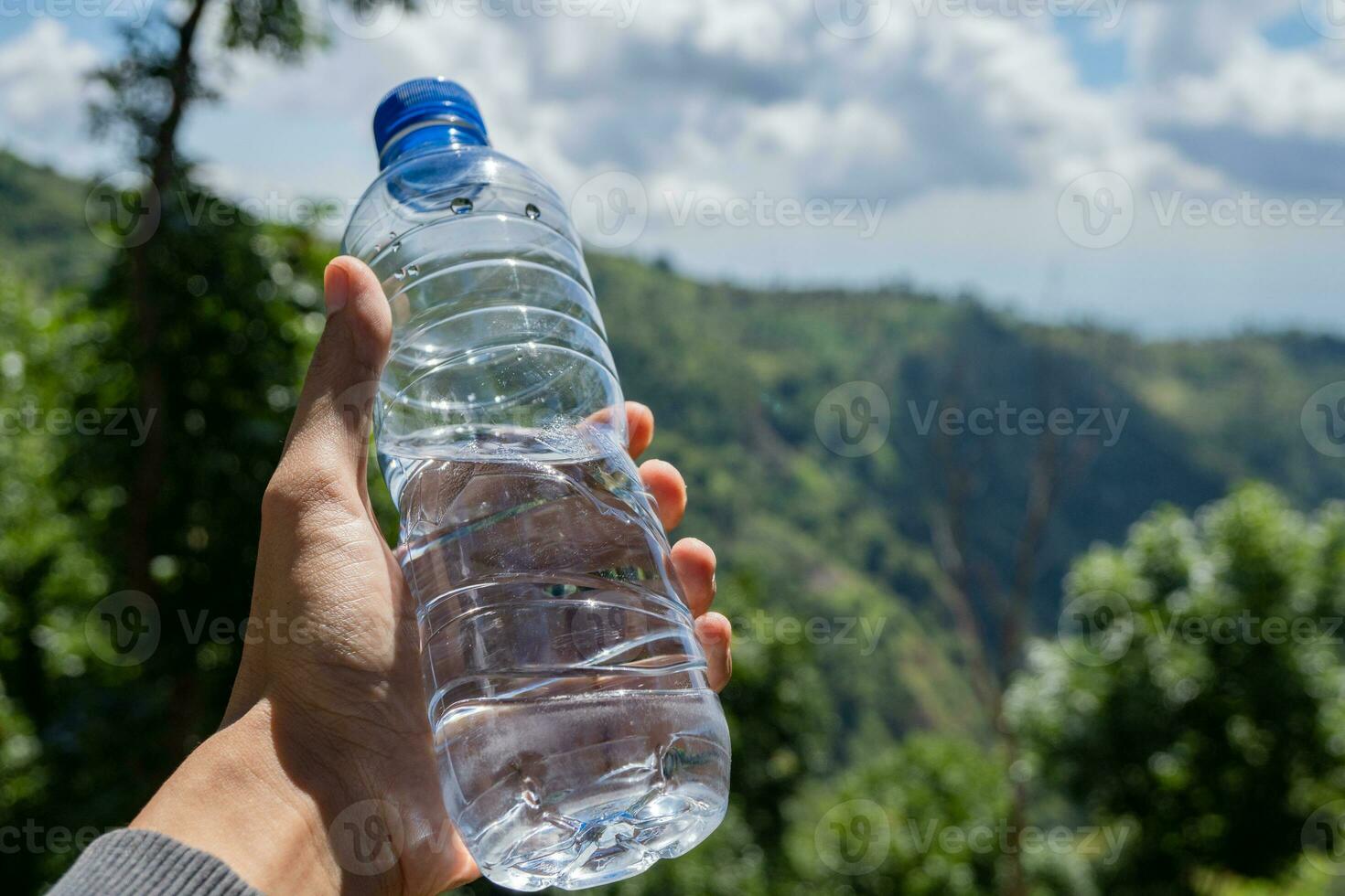 uomo hold minerale acqua su il picco di montagna. foto è adatto per uso per acqua minerale pubblicità, promozione e Salute cura soddisfare media.