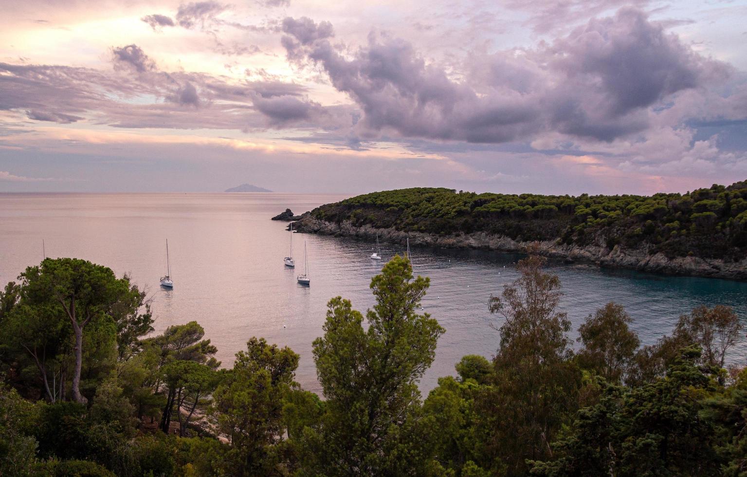 Barche a vela sull'acqua durante il tramonto spettacolare nella baia di fetovaia, isola d'elba, toscana, italia foto