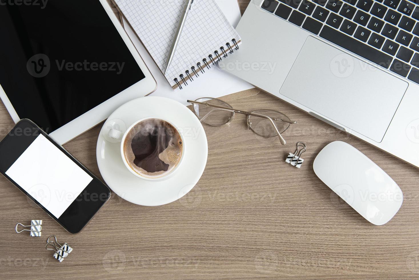 portatile con forniture per ufficio e caffè sul tavolo. foto