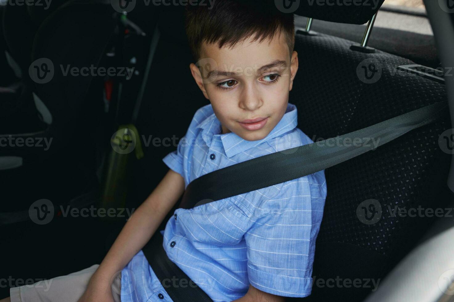 un' ragazzo indossare posto a sedere cinghie viaggi nel un' protettivo bambino auto posto a sedere. in viaggio tranquillamente con bambini foto