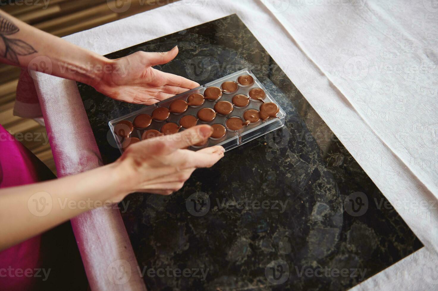 avvicinamento di femmina mani Tenere cioccolato muffe pieno di liquido riscaldato cioccolato massa foto