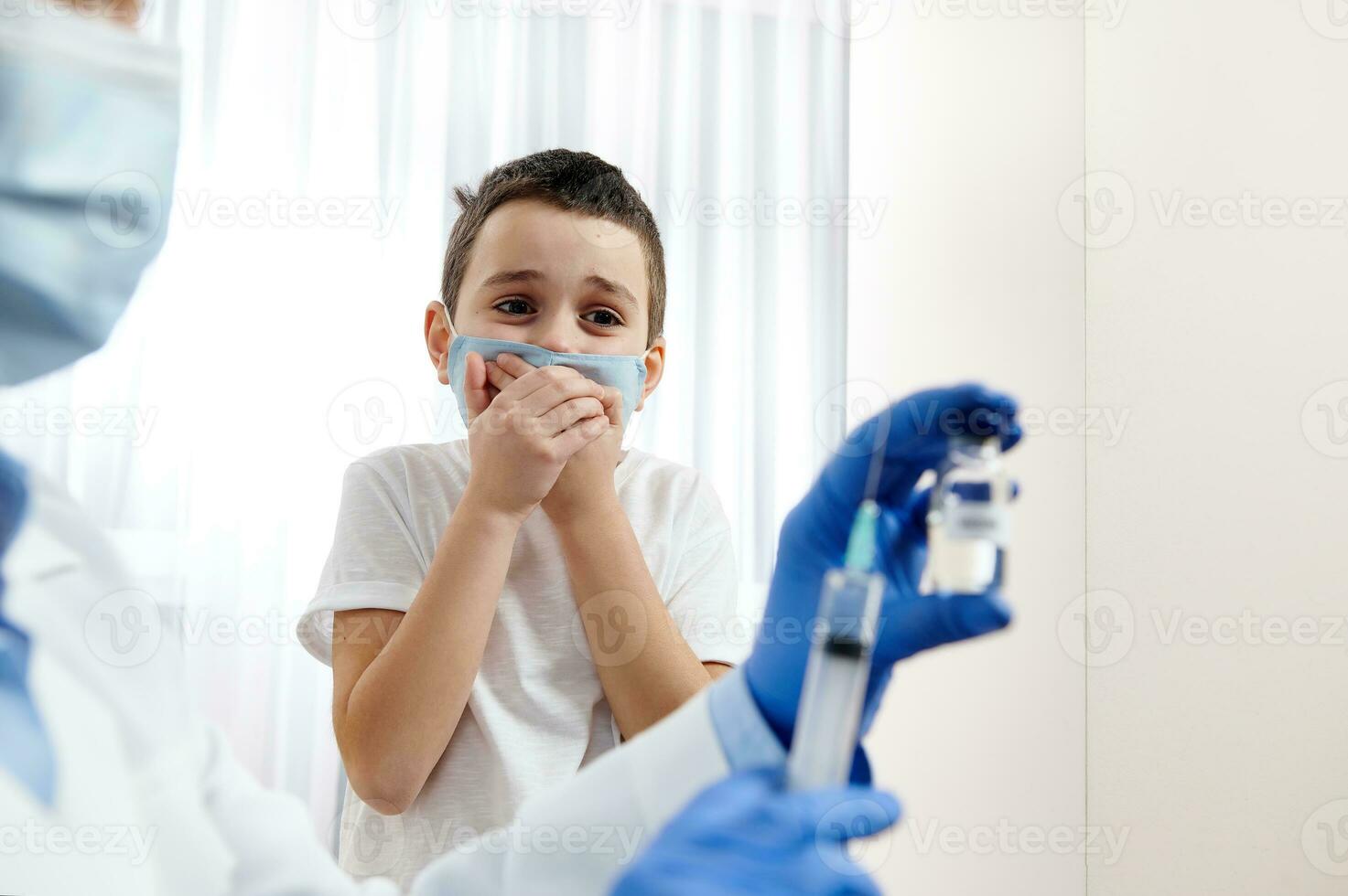 ragazzo impaurito di iniezioni sembra a un' sfocato fiala con vaccino e siringa nel il medico mani foto