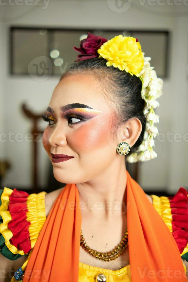 bellissimo viso di un' tradizionale indonesiano ballerino indossare fiori e affascinante trucco prima l'esecuzione foto
