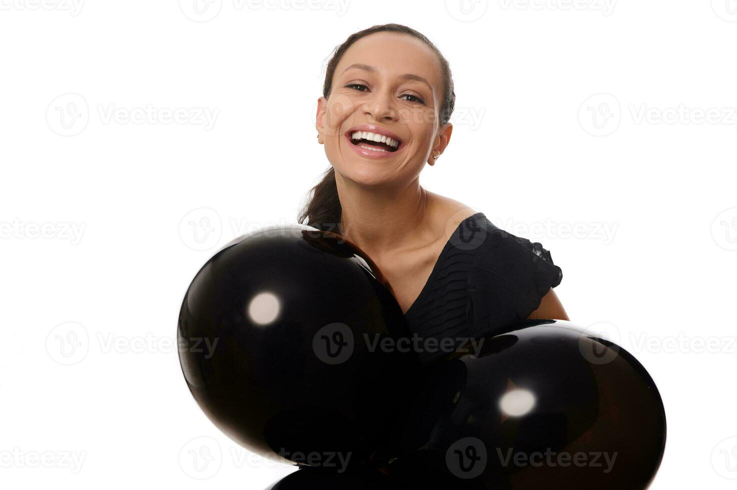 nero Venerdì concetto con un attraente misto gara bella donna con bellissimo trentadue denti Sorridi, vestito nel nero sembra a il telecamera sta con nero aria palloncini contro bianca sfondo, copia spazio. foto