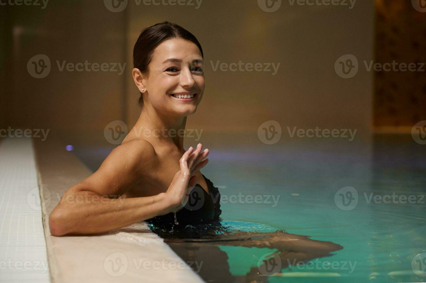 ritratto di un' bellissimo mezzo anziano caucasico donna rilassante nel nuoto termico piscina nel lusso benessere terme ricorrere. purezza, idroterapia, ricreazione, salutare e attivo stile di vita concetto. copia spazio foto