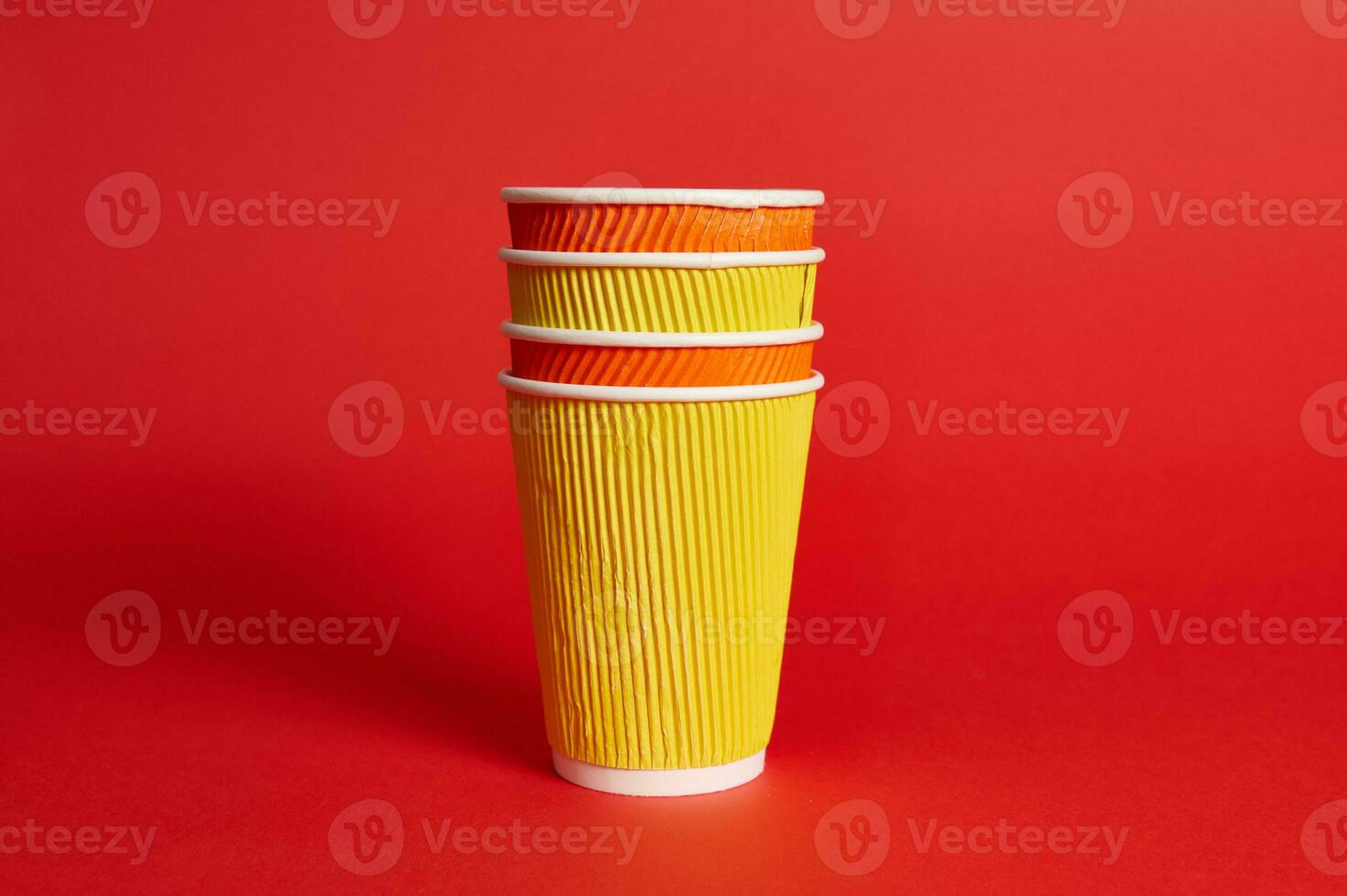 pila di multicolore carta monouso tazze per caldo bevande su un' rosso sfondo con copia spazio. foto