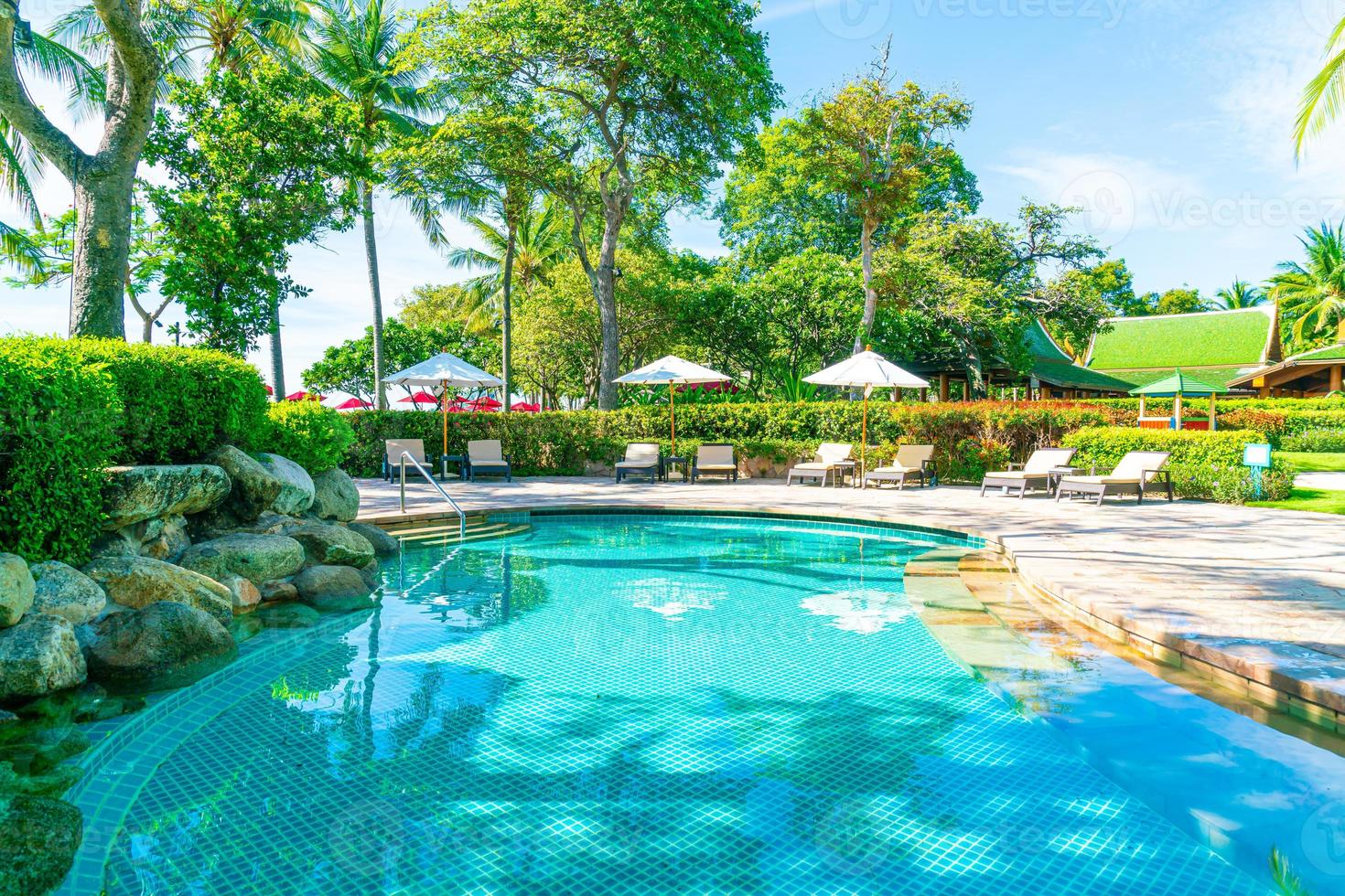 bellissimo ombrellone e sedia intorno alla piscina in hotel e resort foto