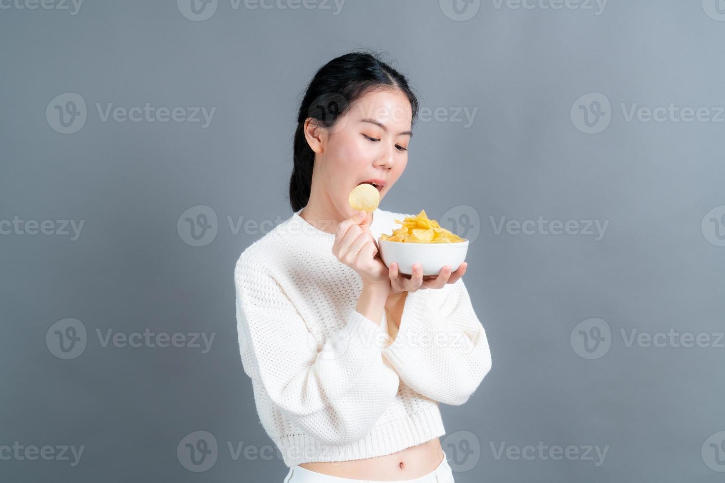 la giovane donna asiatica mangia le patatine fritte foto