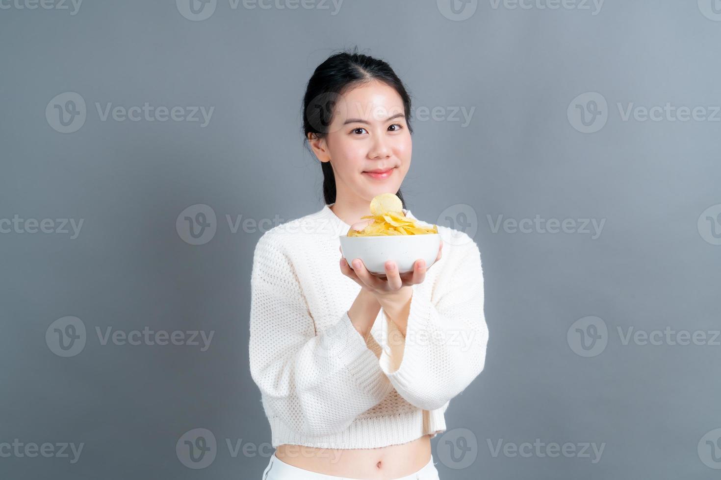 la giovane donna asiatica mangia le patatine fritte foto