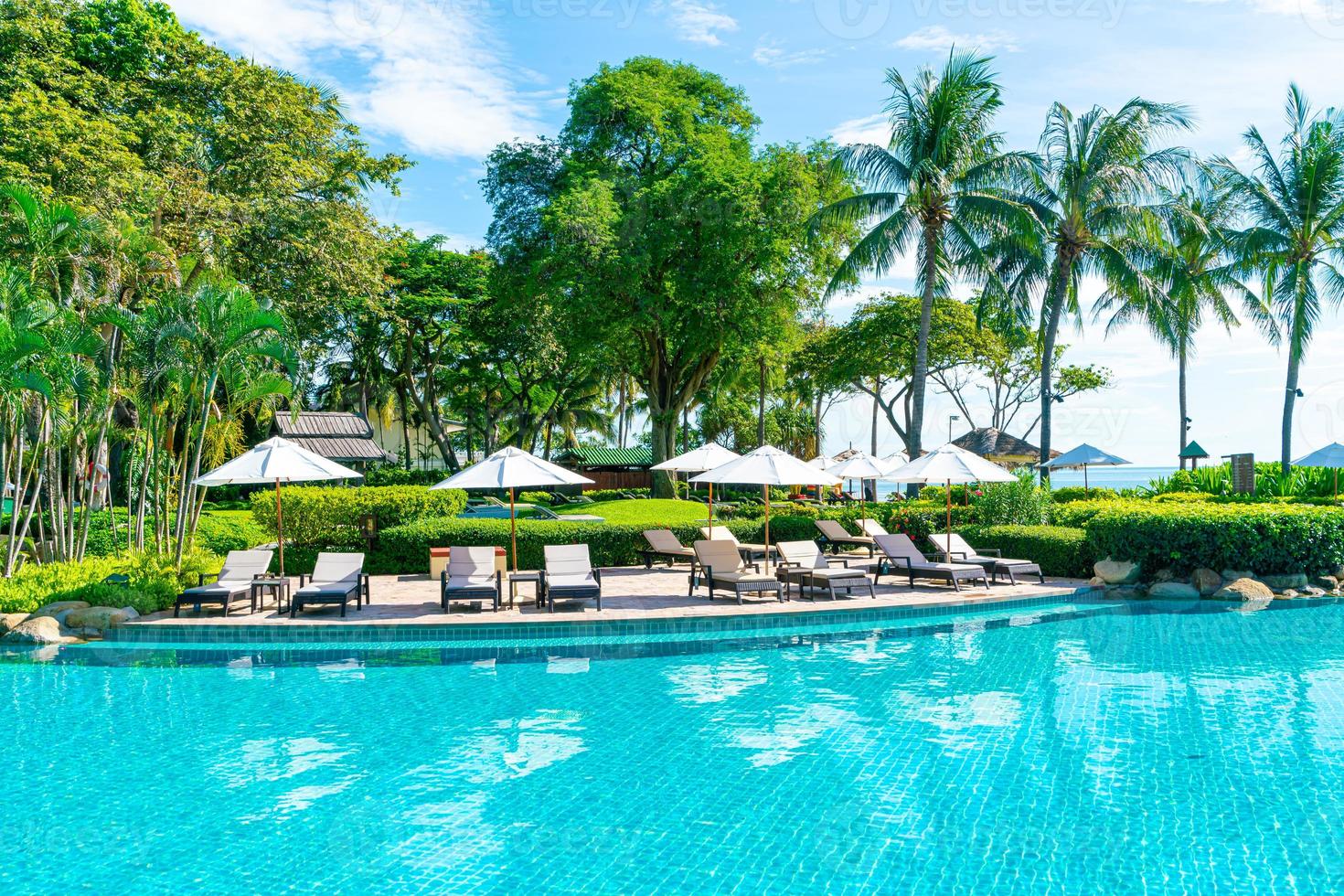 bellissimo ombrellone e sedia intorno alla piscina in hotel e resort foto