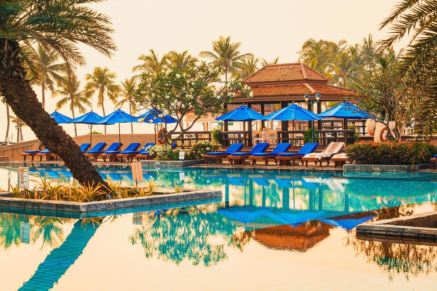 bellissimo ombrellone e sedia intorno alla piscina in hotel e resort foto