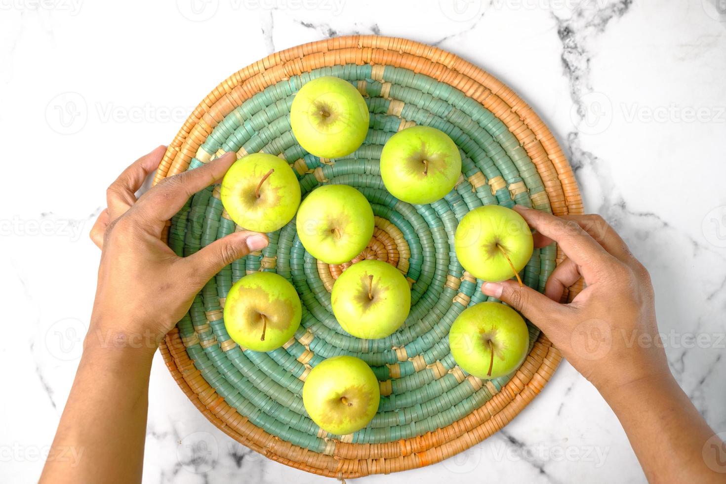 mano che tiene mela verde su sfondo di piastrelle foto