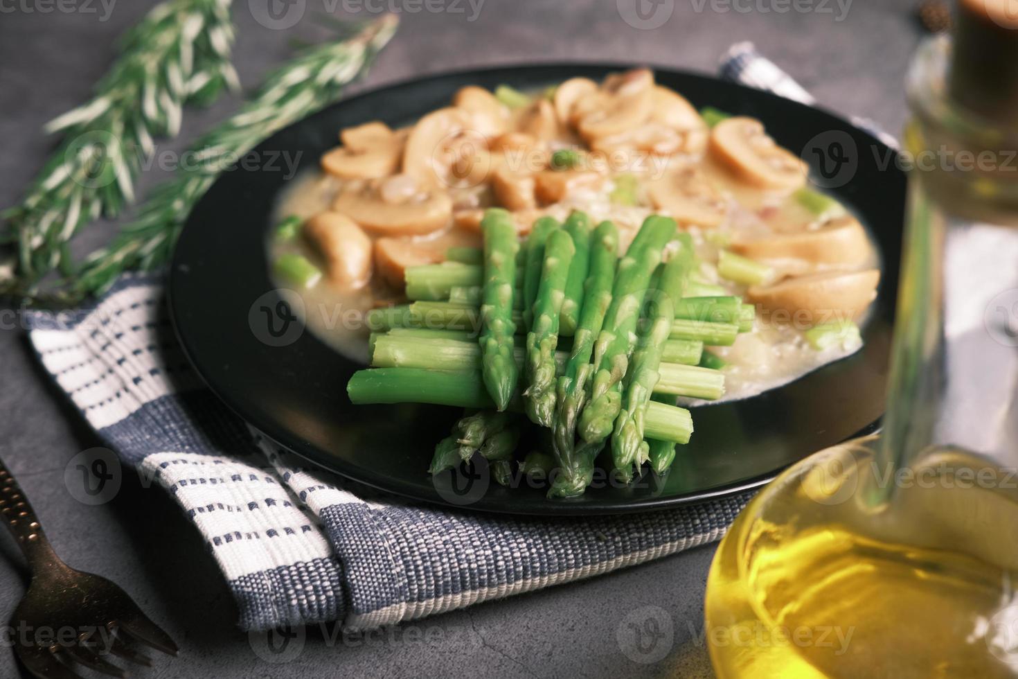 asparagi verdi, olio d'oliva e funghi su fondo piatto nero foto