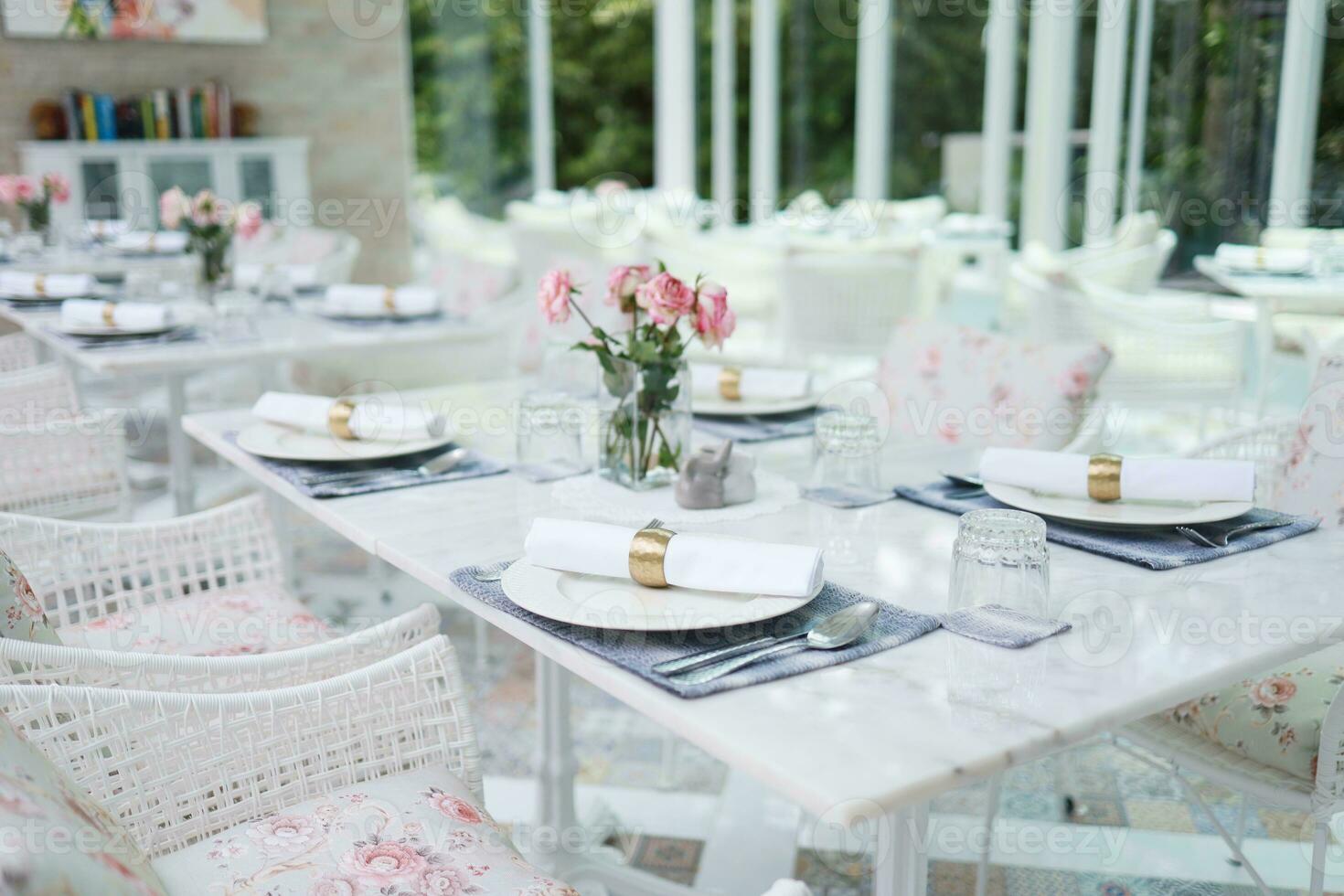 il nozze arredamento. tavoli impostato per un evento festa o nozze ricezione. lusso elegante tavolo ambientazione cena nel un' ristorante. bicchieri e piatti. sala per banchetti e matrimoni. foto