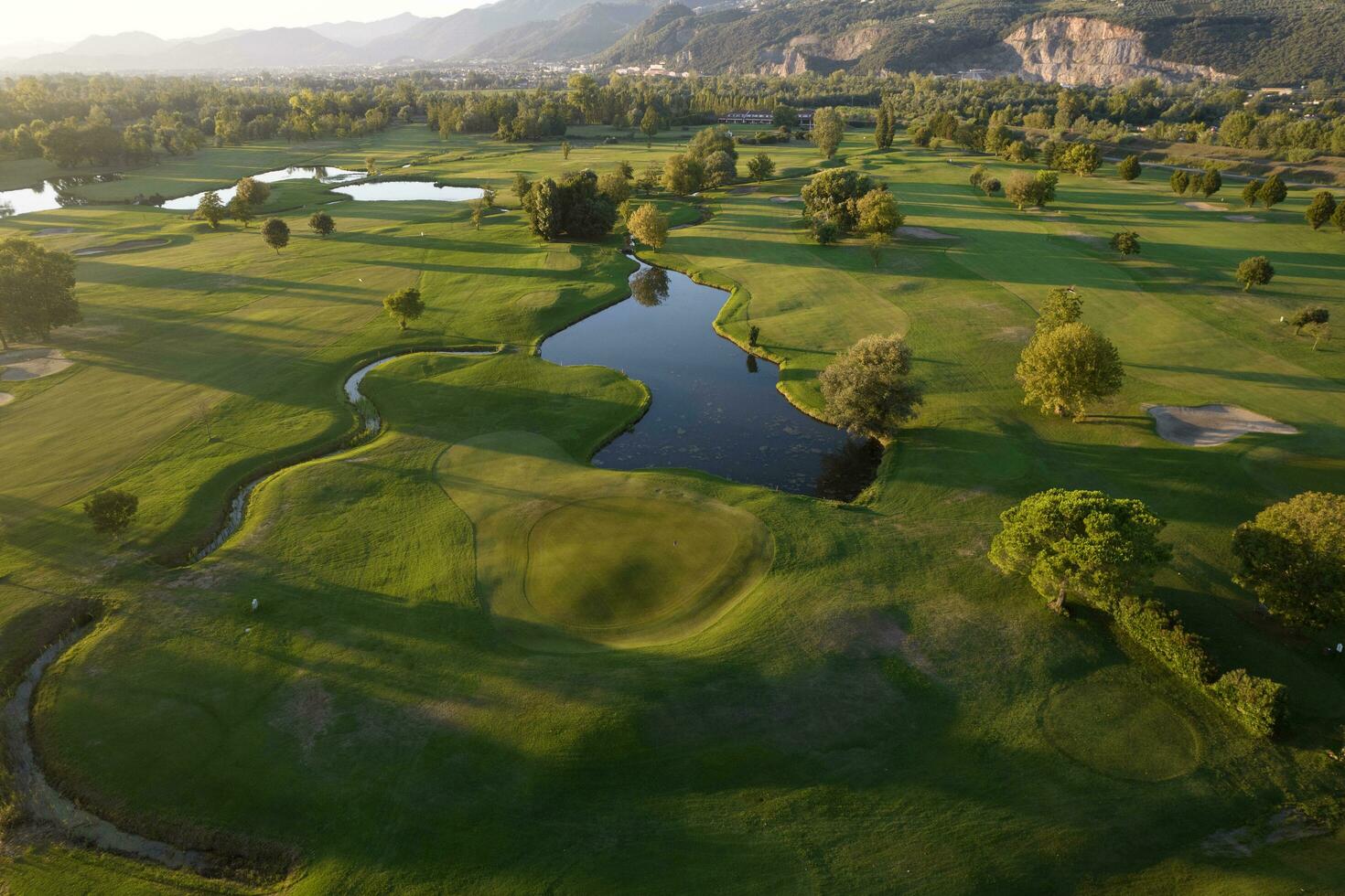 aereo Visualizza di un' verde golf corso a tramonto foto